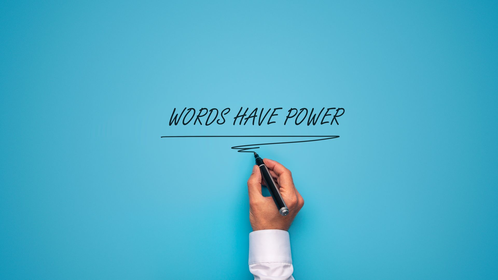 A man scribbles a line underneath 'WORDS HAVE POWER