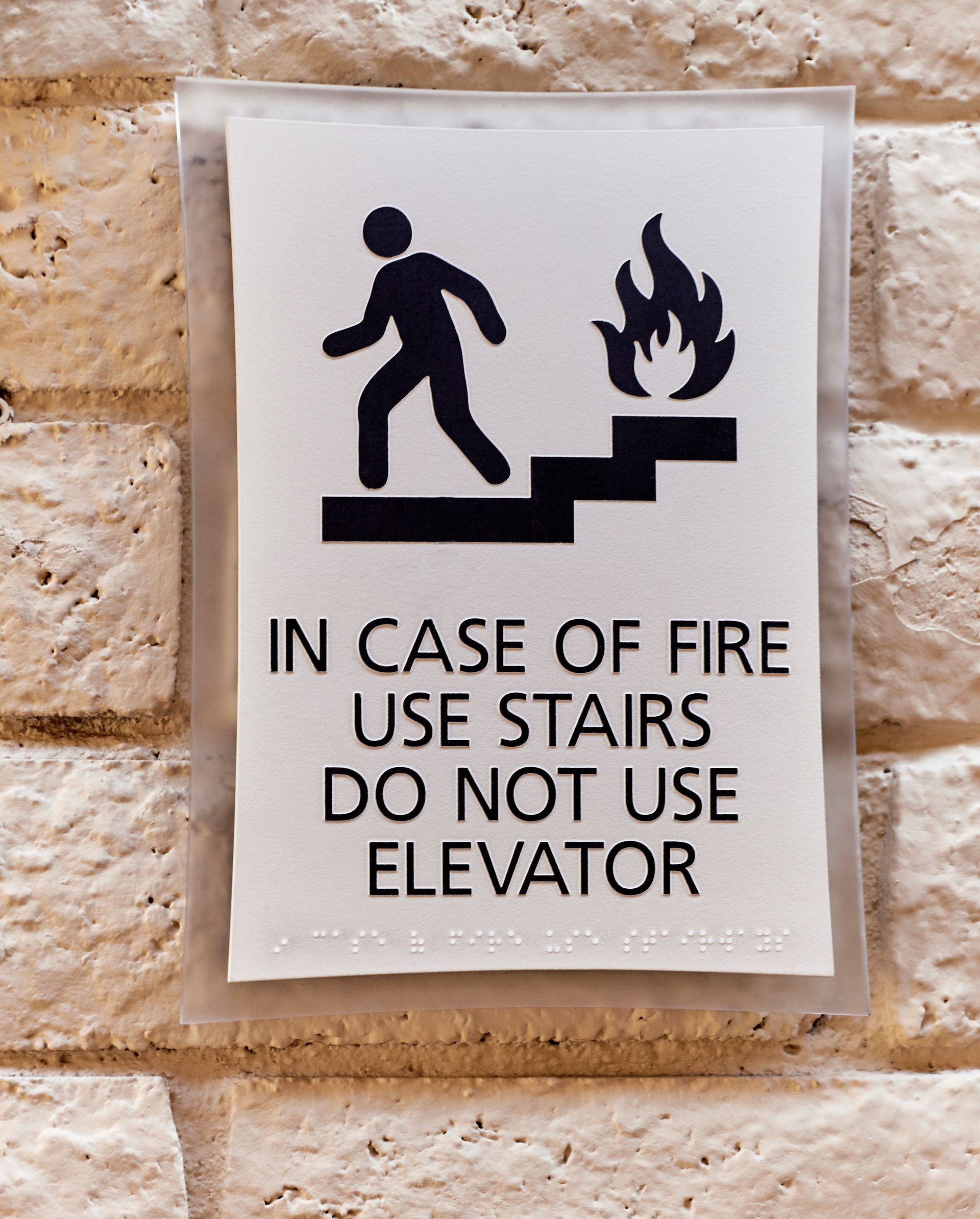 A sign which says 'In case of Fire, Use Stairs' in standard text and braille.