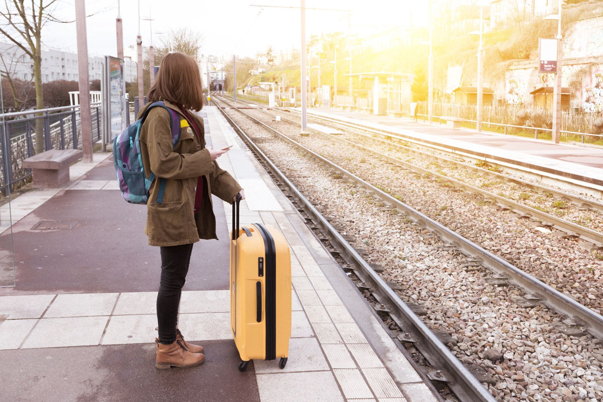 A young woman standing at a train station with no visible accessibility features.