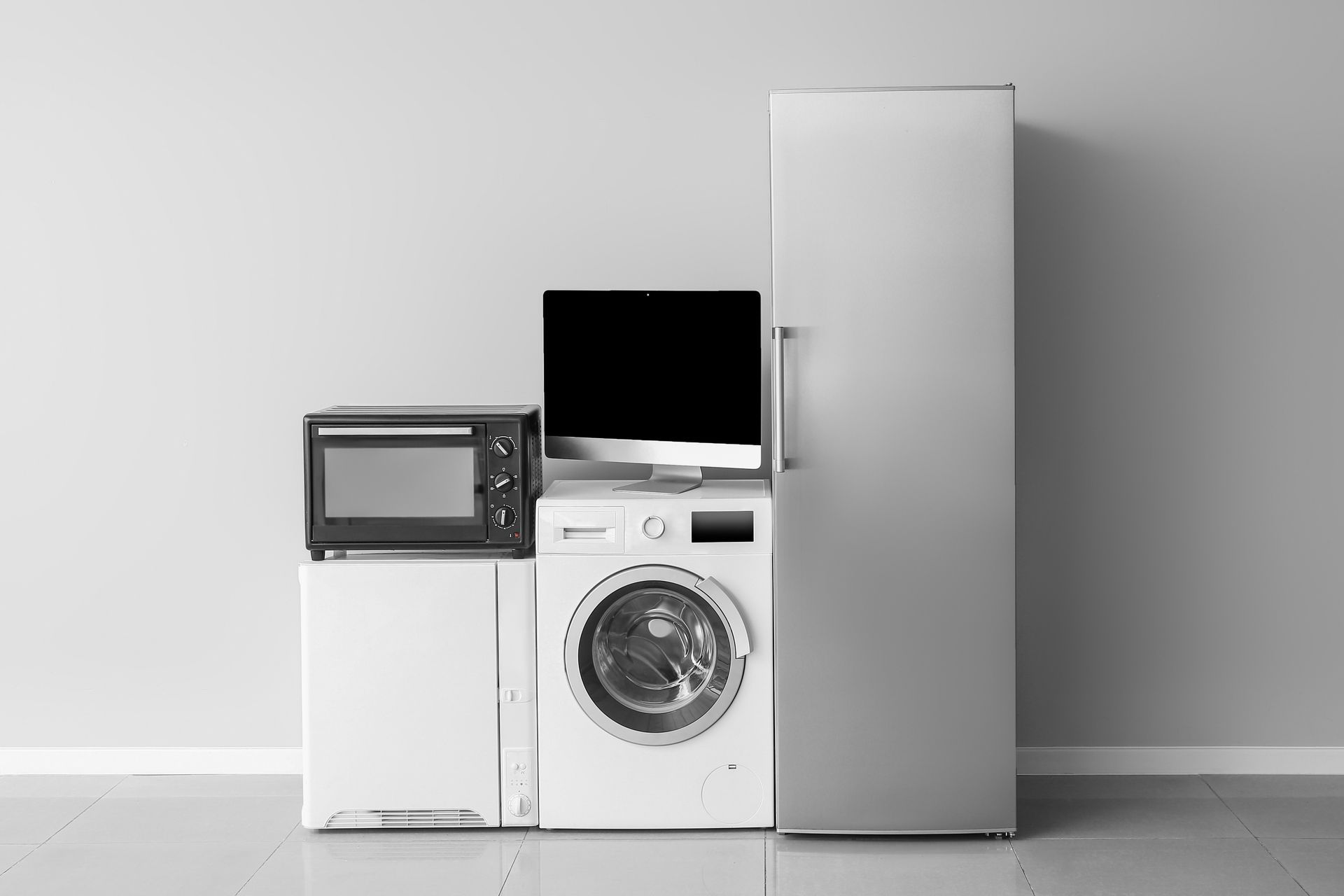 Photo of a selection of modern home appliances, including a fridge, washing machine, and microwave.