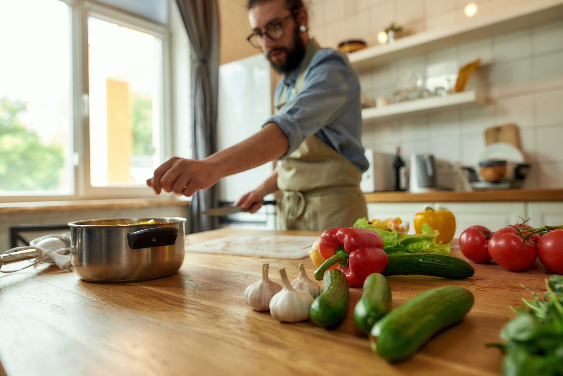 Photo of a man preparing a meal with a selection of fresh vegetables on the work surface. 