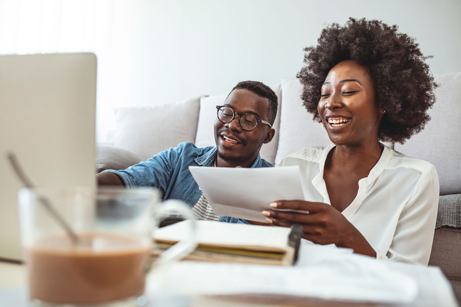 Photograph of a man and woman smiling while reviewing paperwork and working on a laptop. 