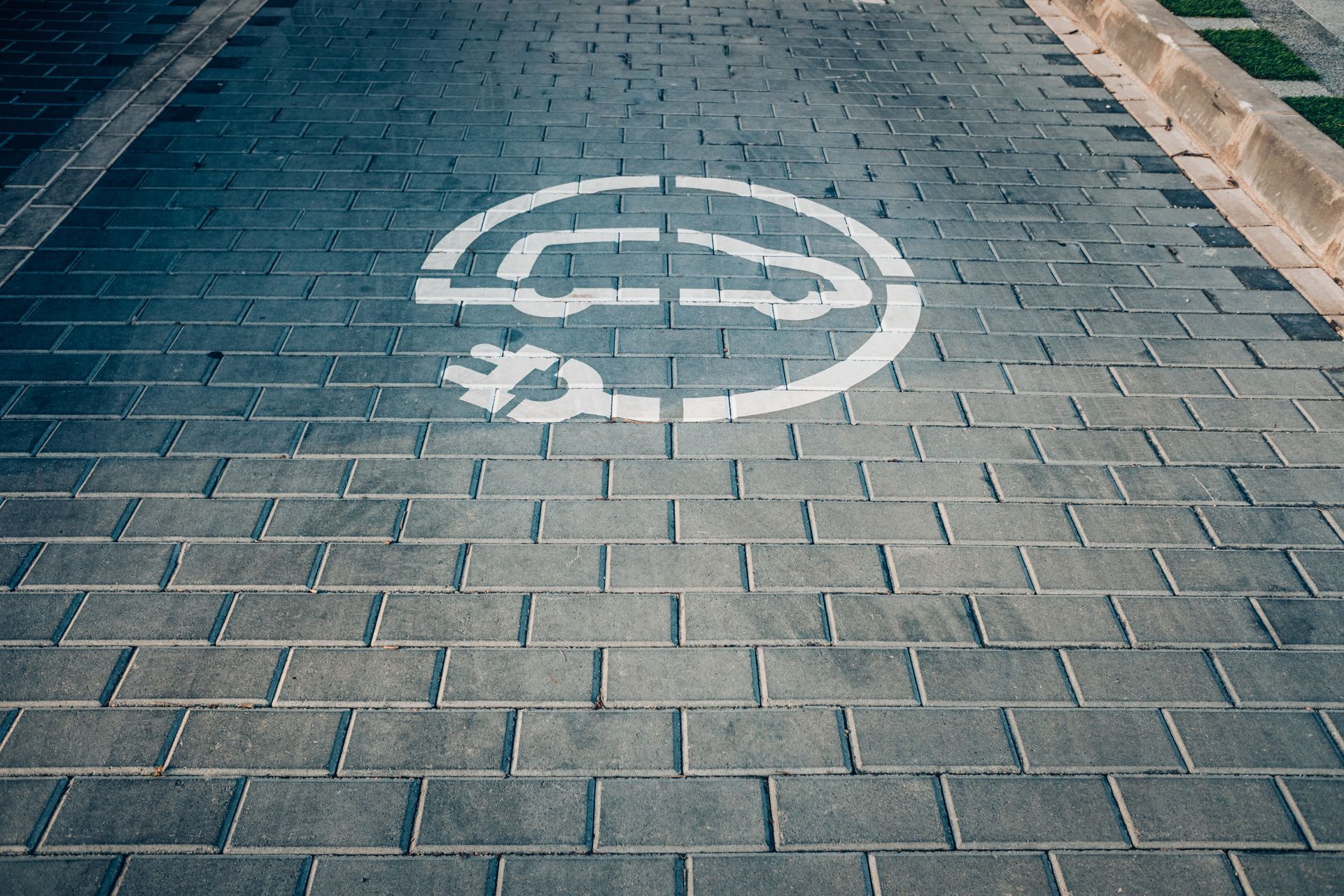 Photograph of a road with a symbol representing electric vehicles painted on the bricks.