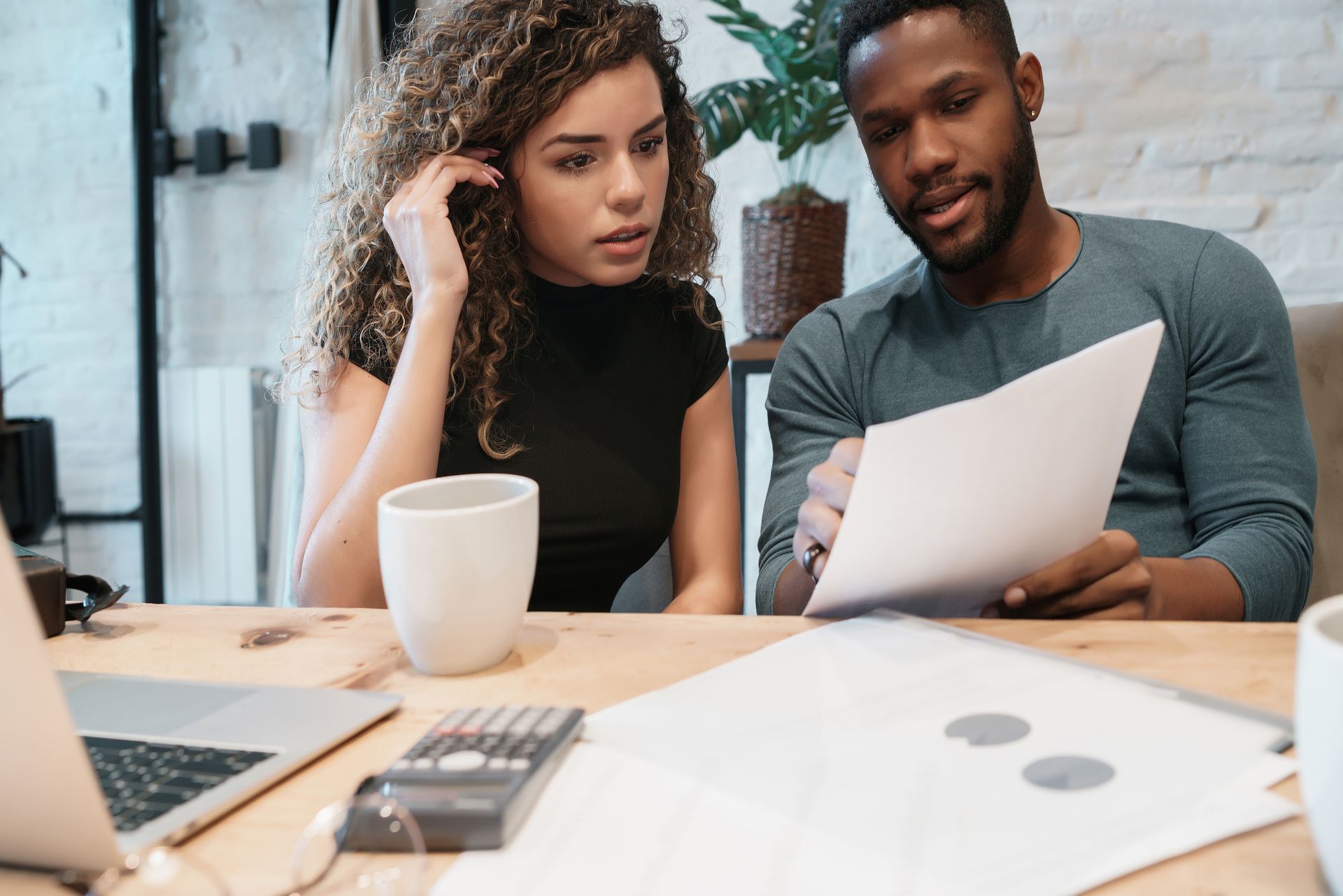 Photo of a young couple sitting at a desk and reviewing a financial document. 