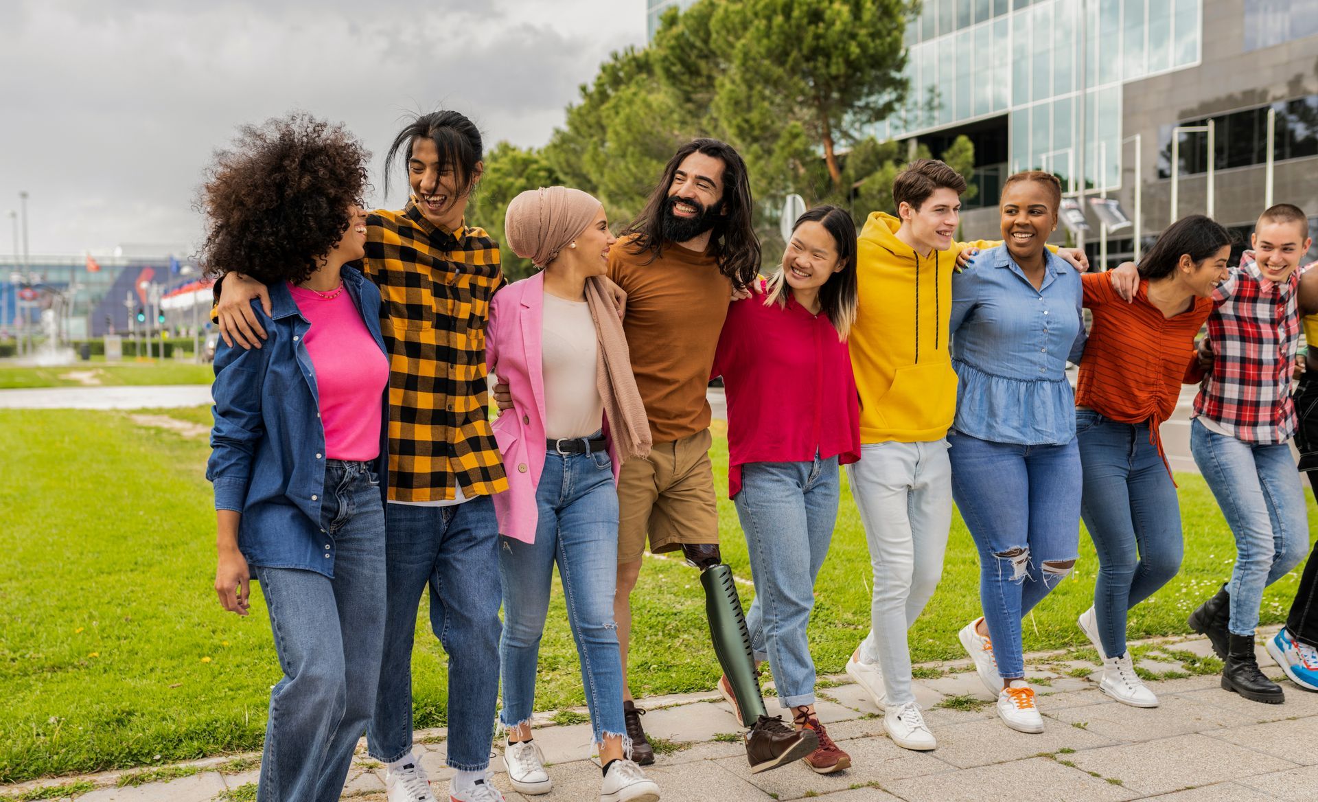 A group of diverse friends walk together in a line while laughing. 