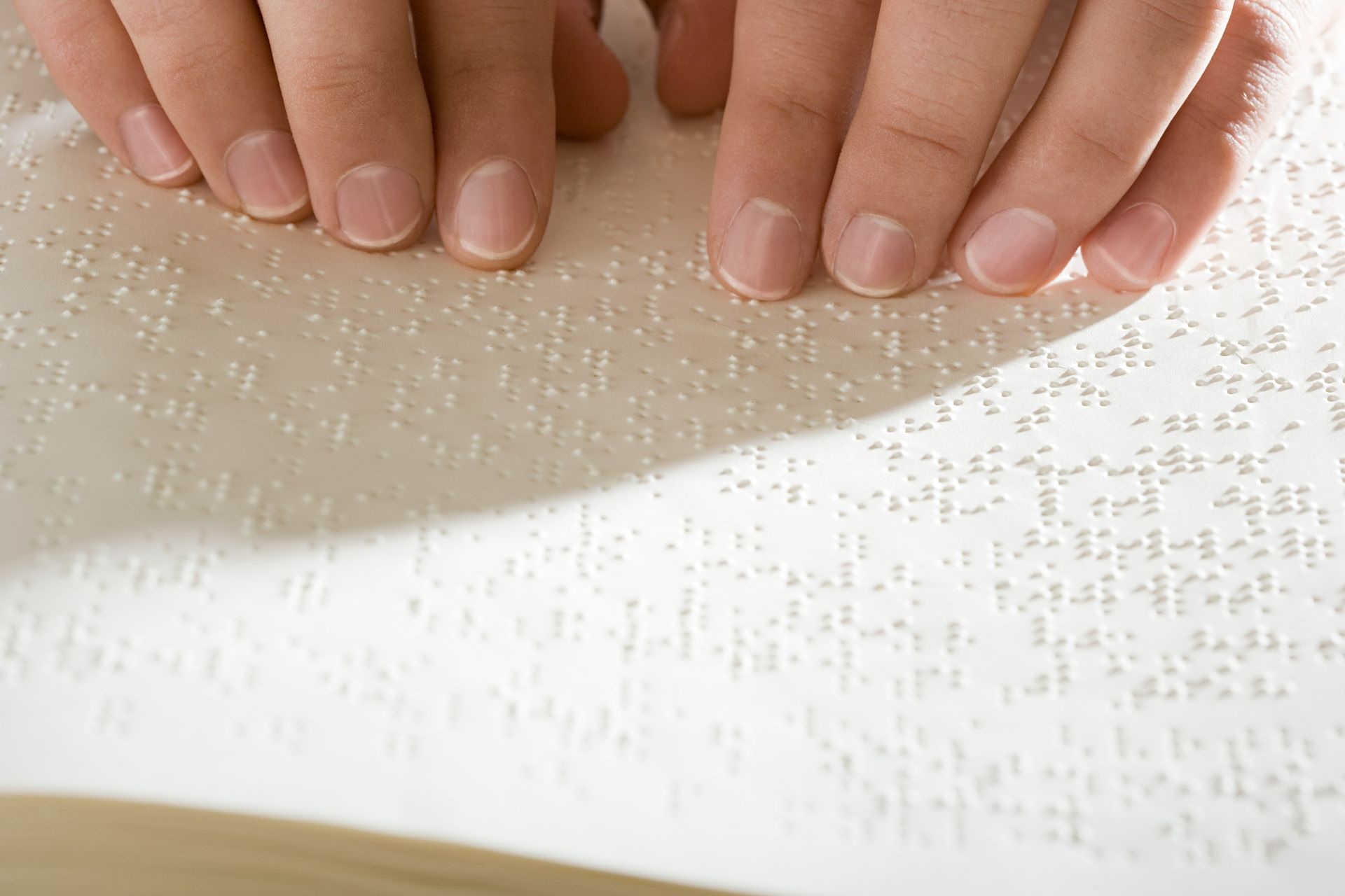 (Touch & Tactile Feedback) Fingertips run over a book written in Braille.