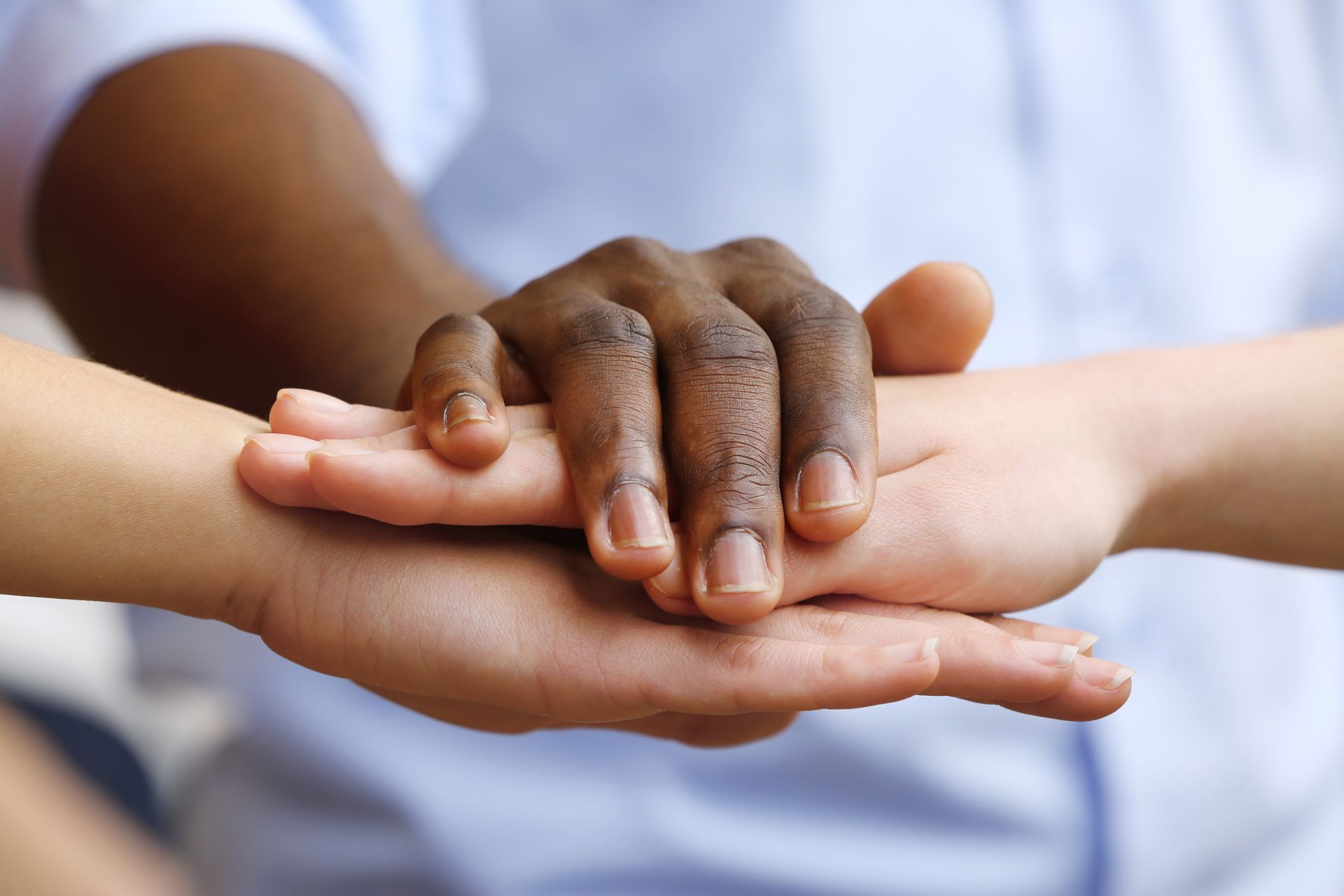 Three people stack their hands atop one another's.