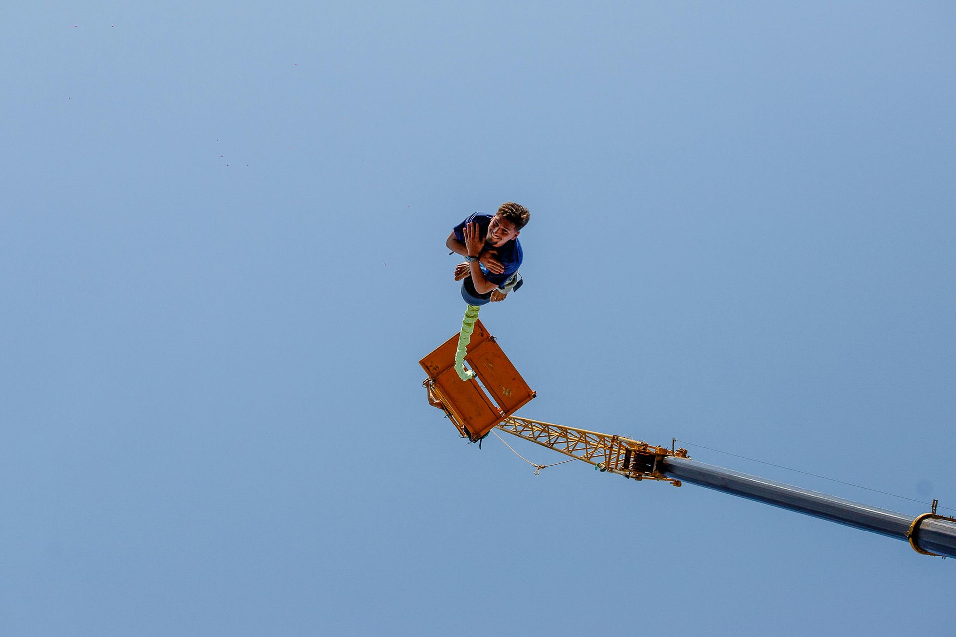 a person suspended mid-air during a bungee jump, arms outstretched, embodying surrender and belief