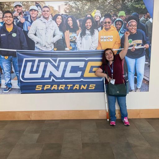 Haley Valente in front of a poster for UNCG Spartans.