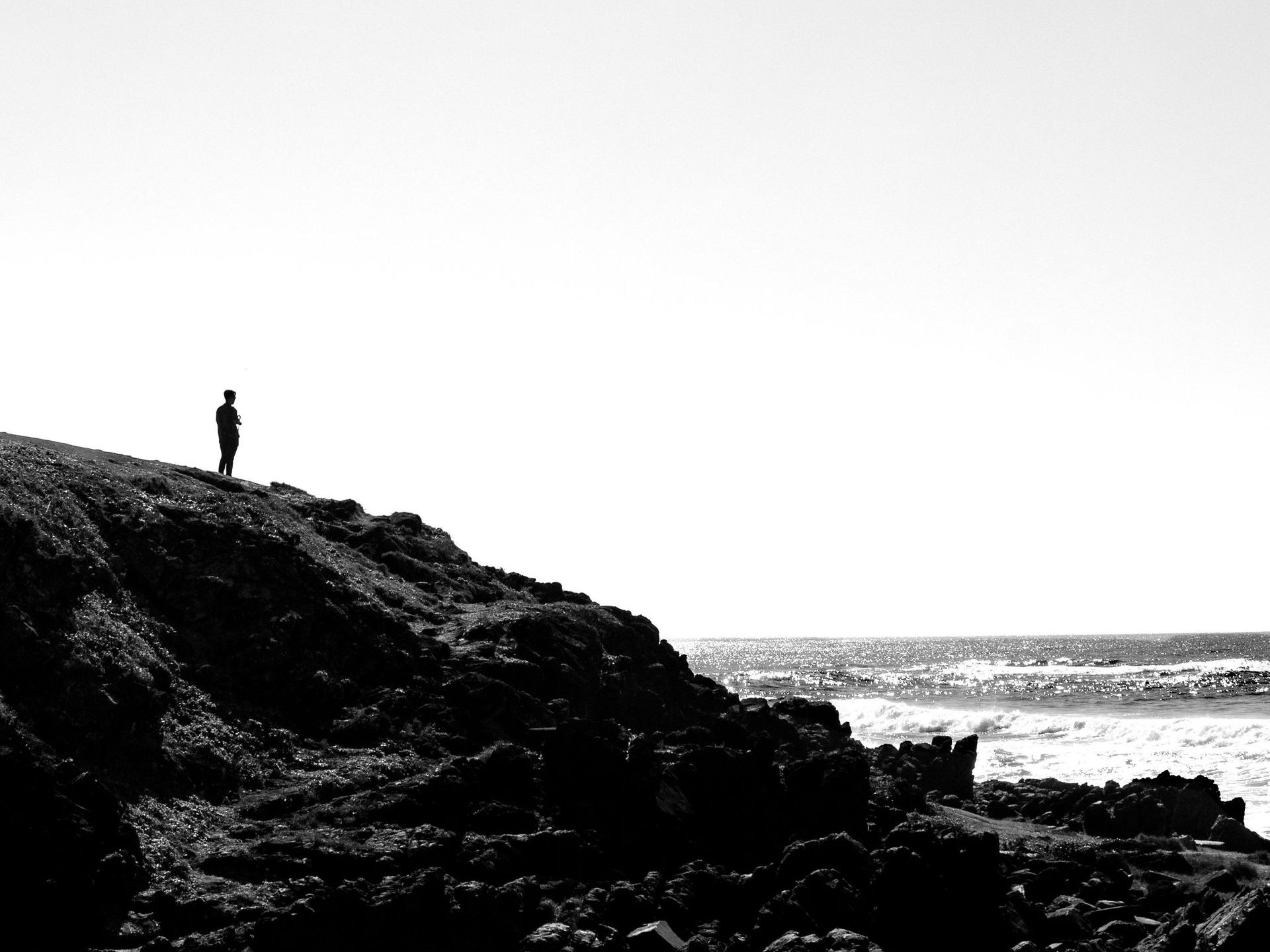 a solitary figure standing at the edge of a cliff looking out across misty mountains, reflecting inner trust and personal reflection