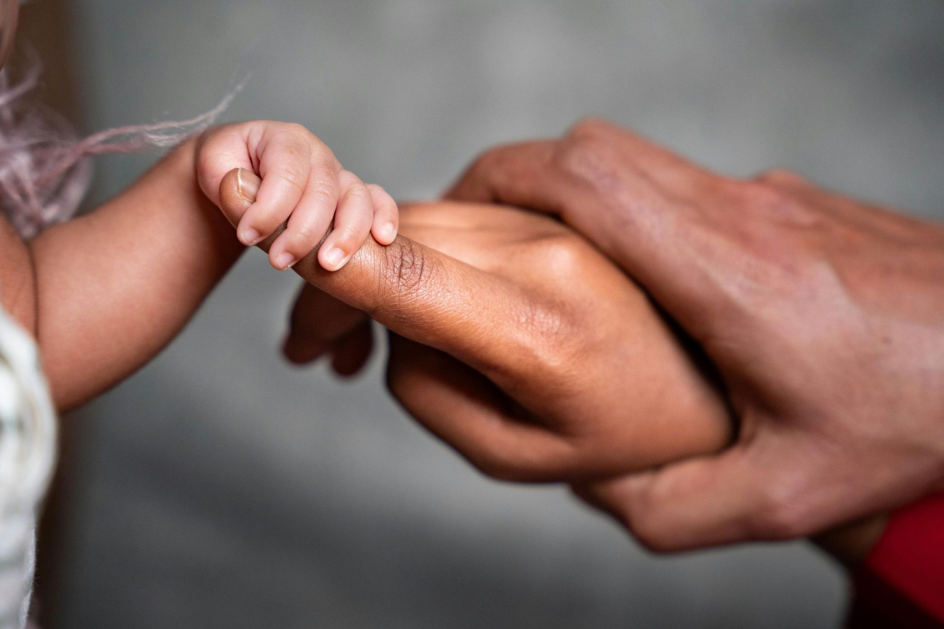a newborn’s tiny hand gently grasping an adult finger, reflecting the emotional bonds formed before language