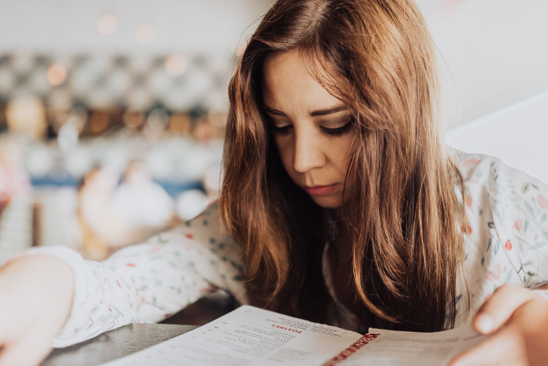 (Restaurant Hide and Seek) A young woman flicks through the restaurant menu, alone in a busy restaurant.