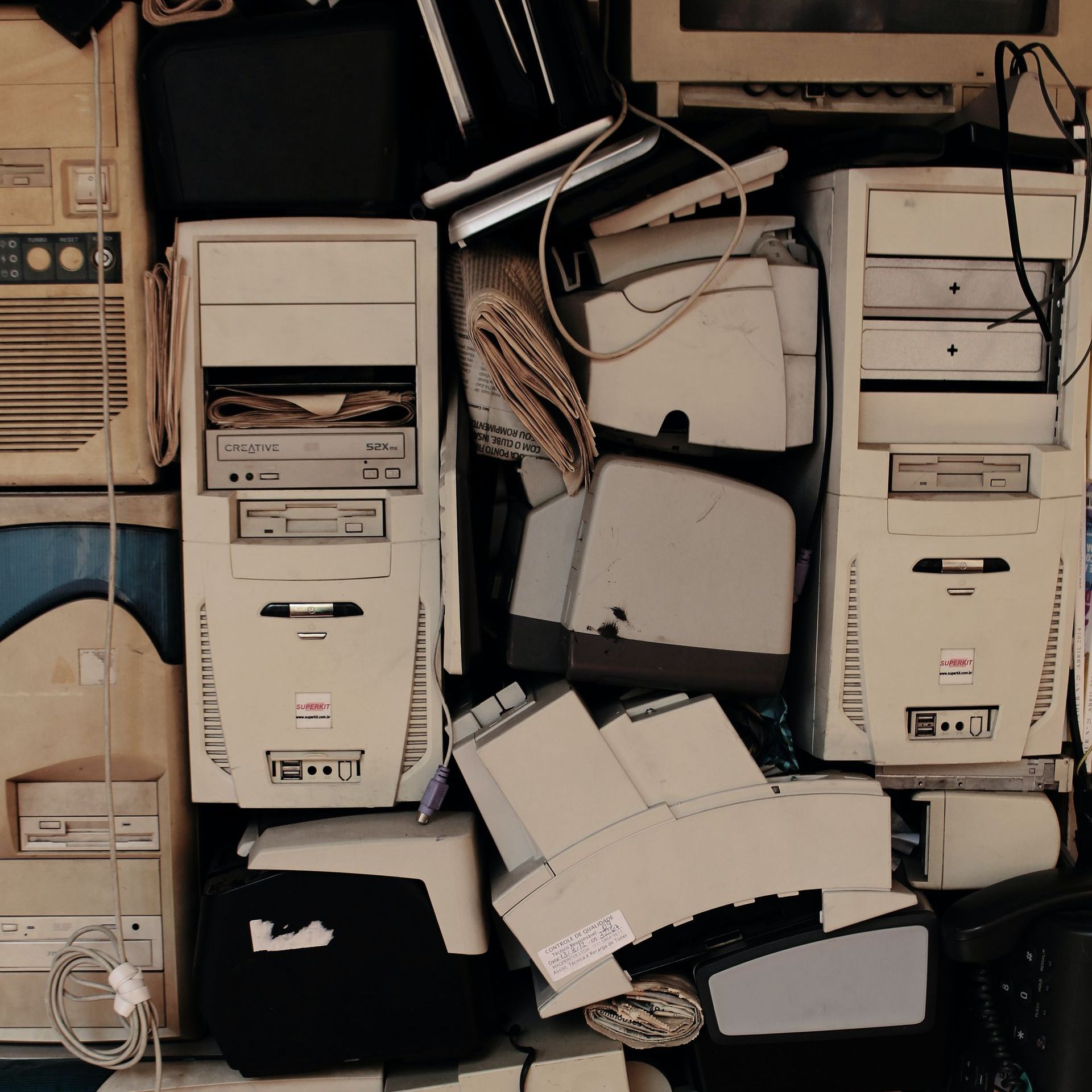 A stack of disused and obsolete computer equipment including keyboards, computer towers, and monitors.