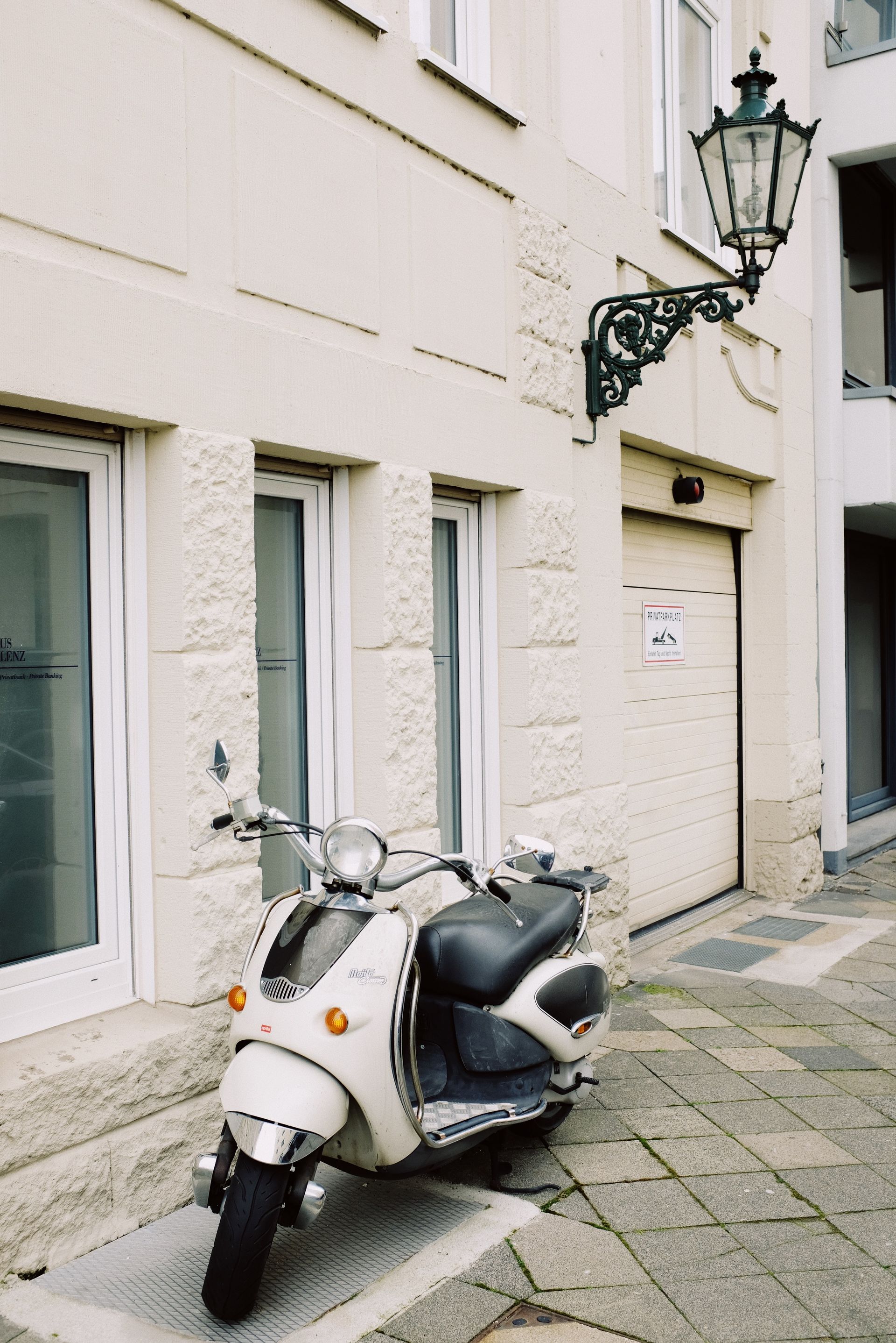 Retro scooter parked on the pavement in front of a modern building.