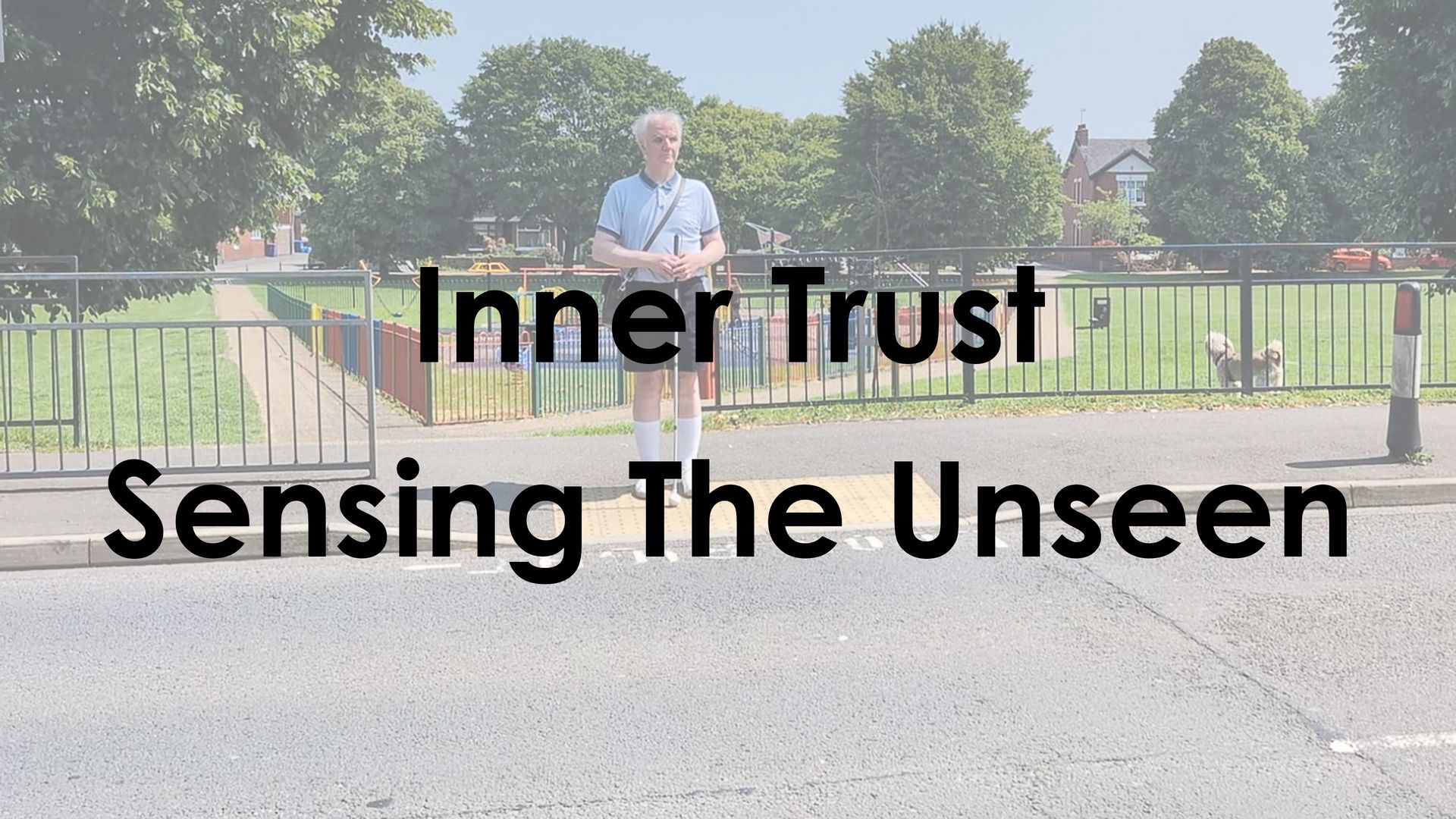 A person with sight loss standing at the edge of a pavement with a white cane, listening carefully.
