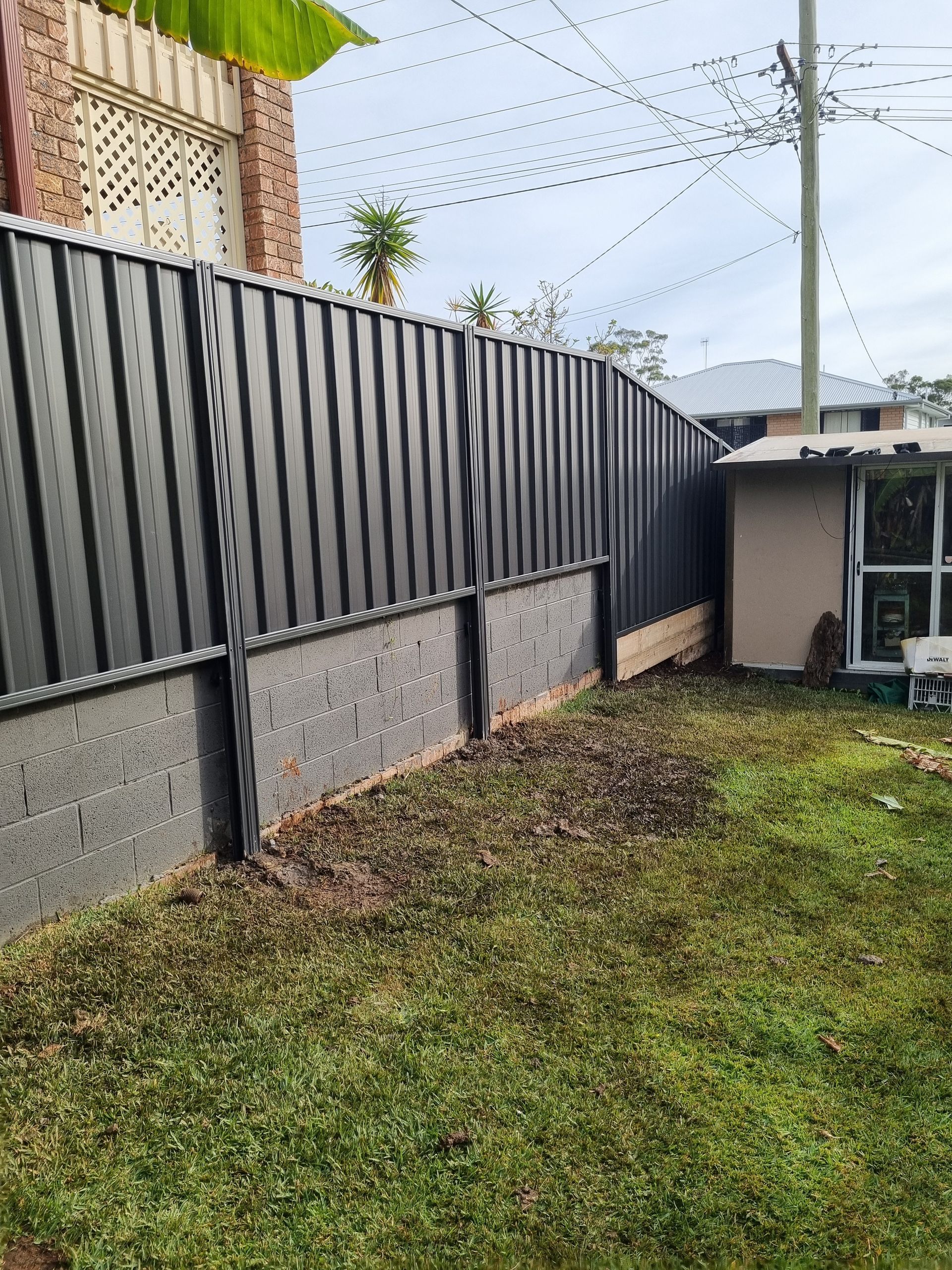 A Black Metal Fence Surrounds a Swimming Pool — Strike Fencing & Gates in Bateau Bay, NSW