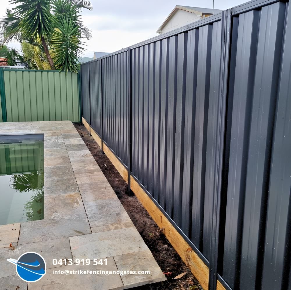 A Black Fence is Surrounding a Pool in a Backyard — Strike Fencing & Gates in Umina, NSW