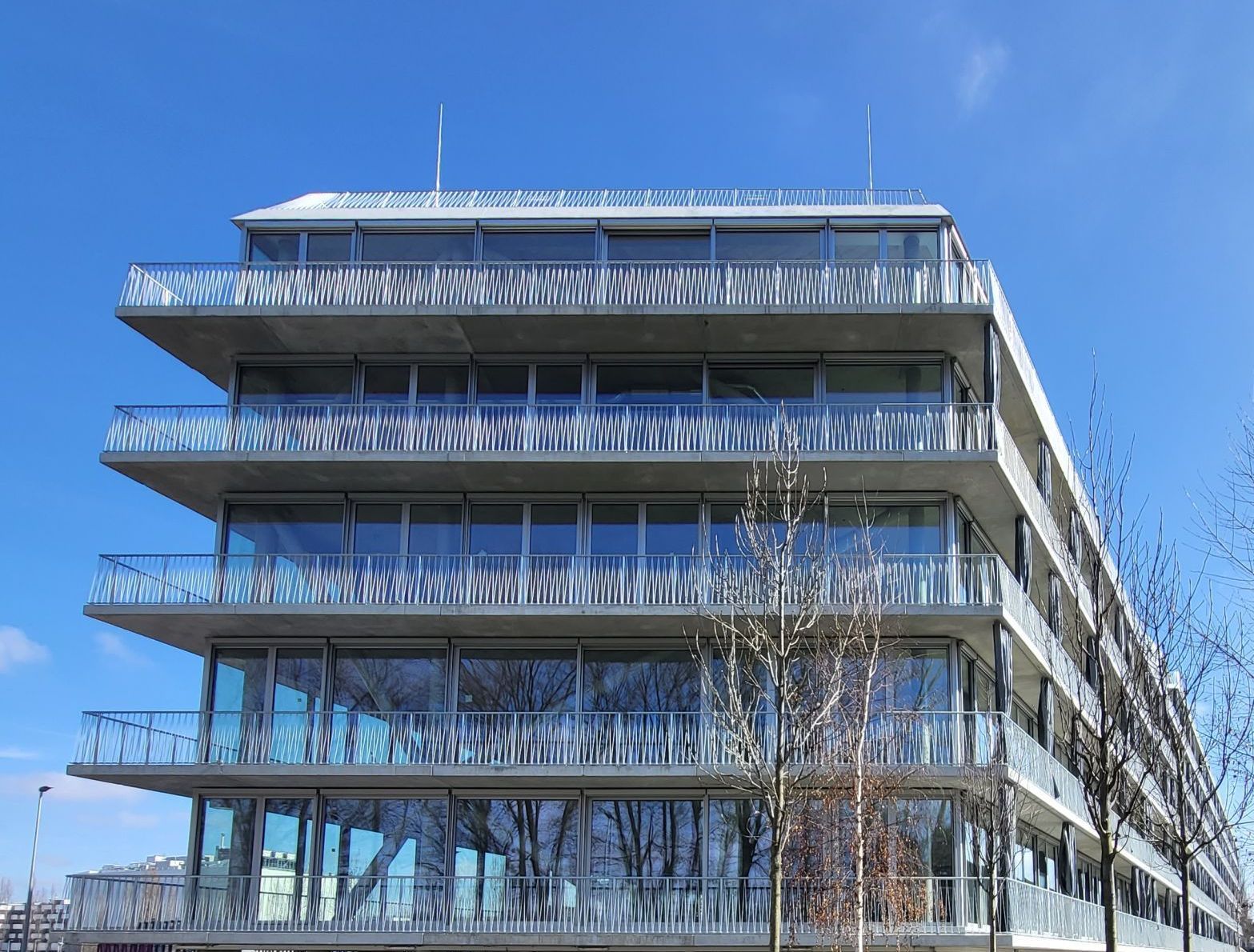 Ein großes Gebäude mit vielen Fenstern und Balkonen an einem sonnigen Tag.