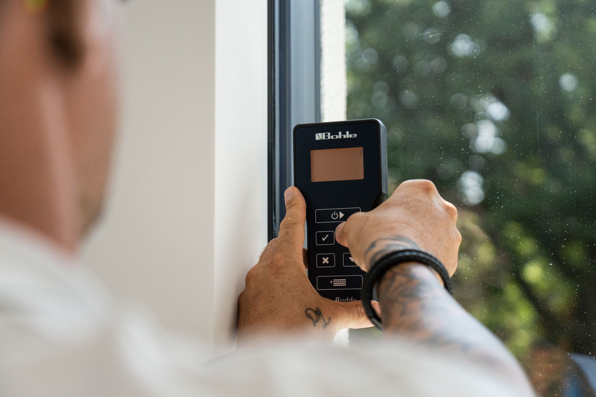 Ein Mann bedient ein Smartphone, um ein Fenster zu steuern.