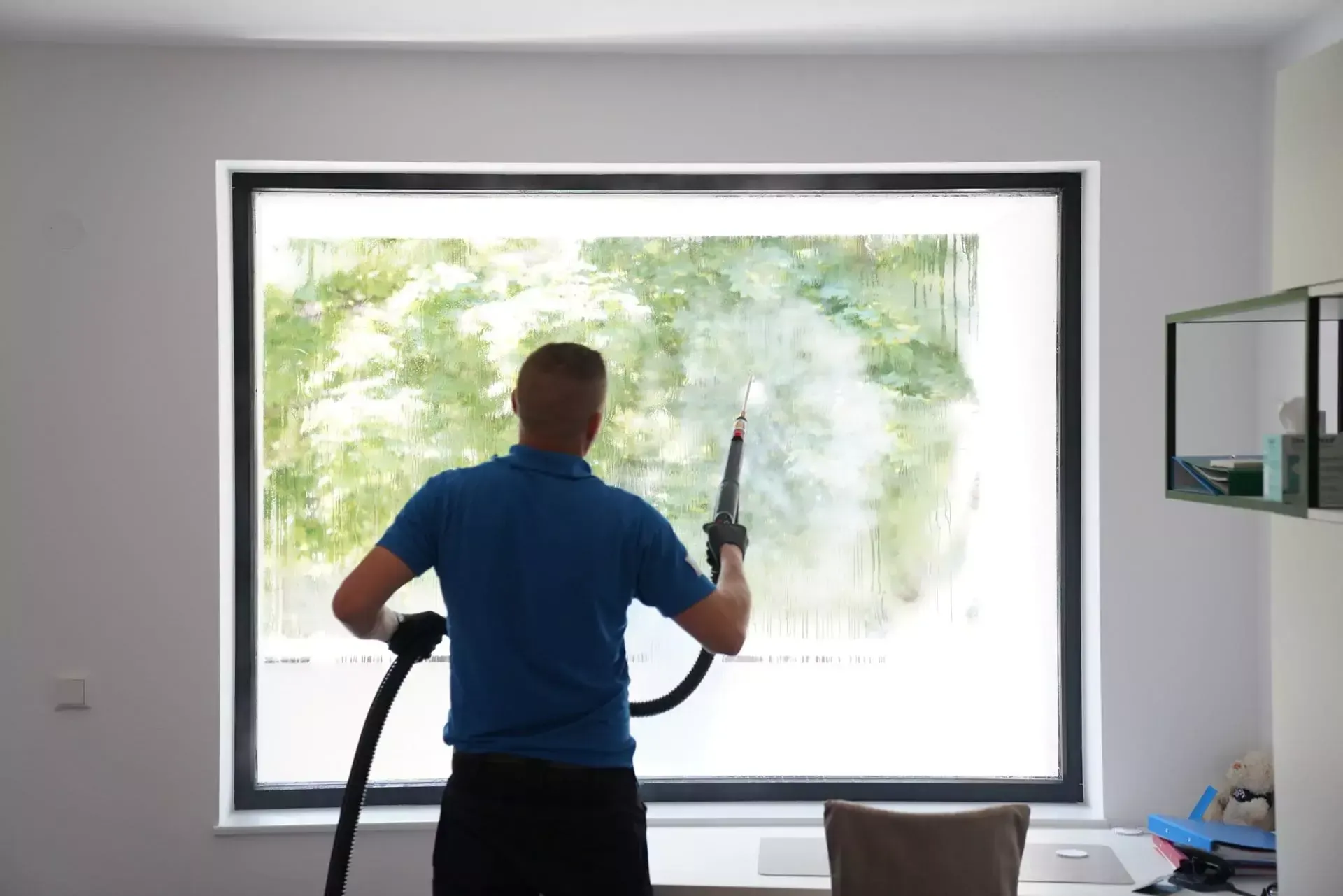 Ein Mann putzt ein Fenster mit einem Staubsauger.