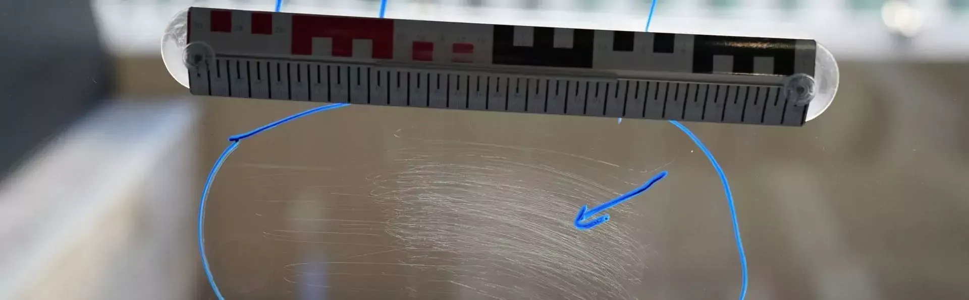 Mit einem Lineal wird ein Fingerabdruck auf einem Blatt Papier gemessen.