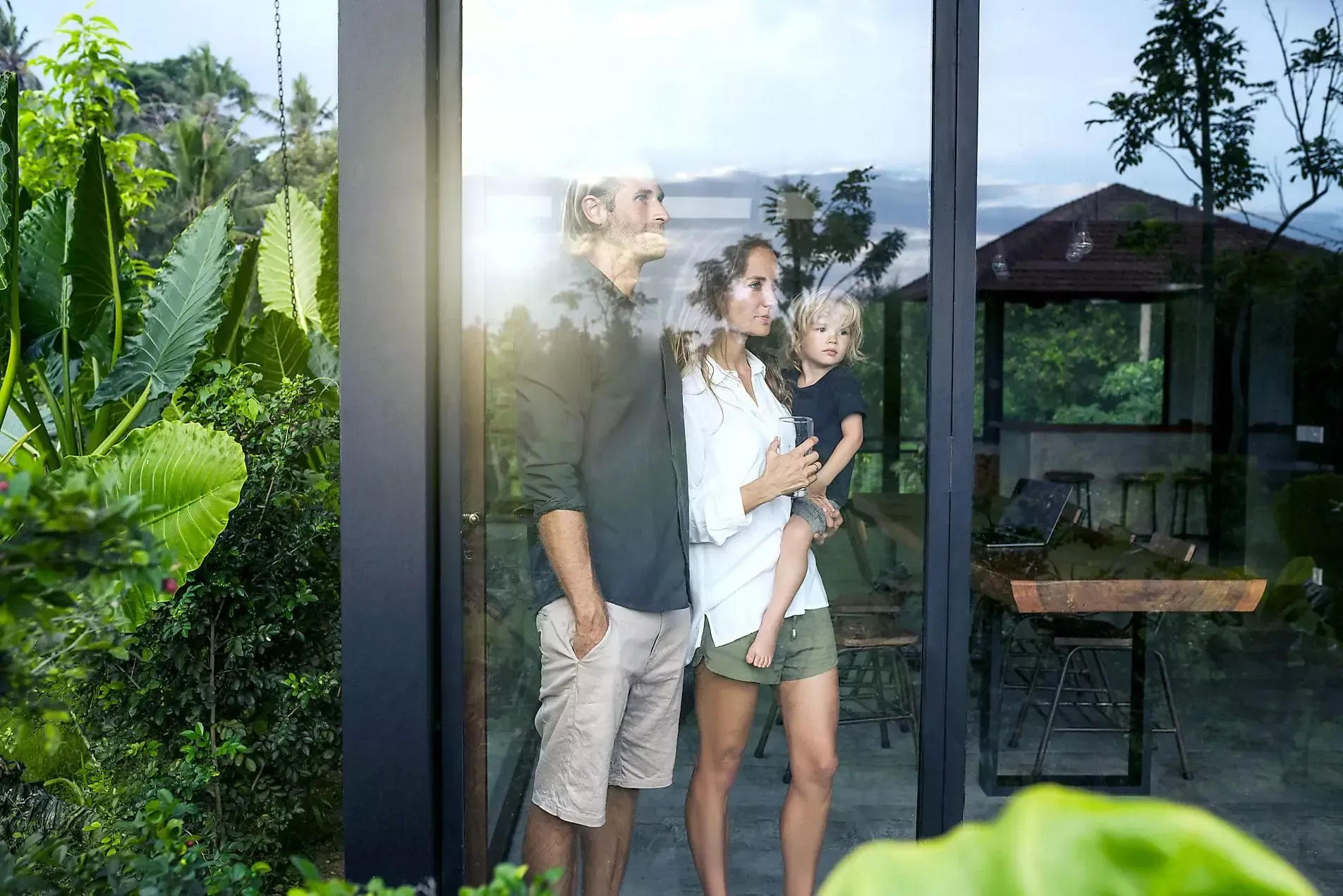 Eine Familie steht vor einer Glastür und schaut hinaus.