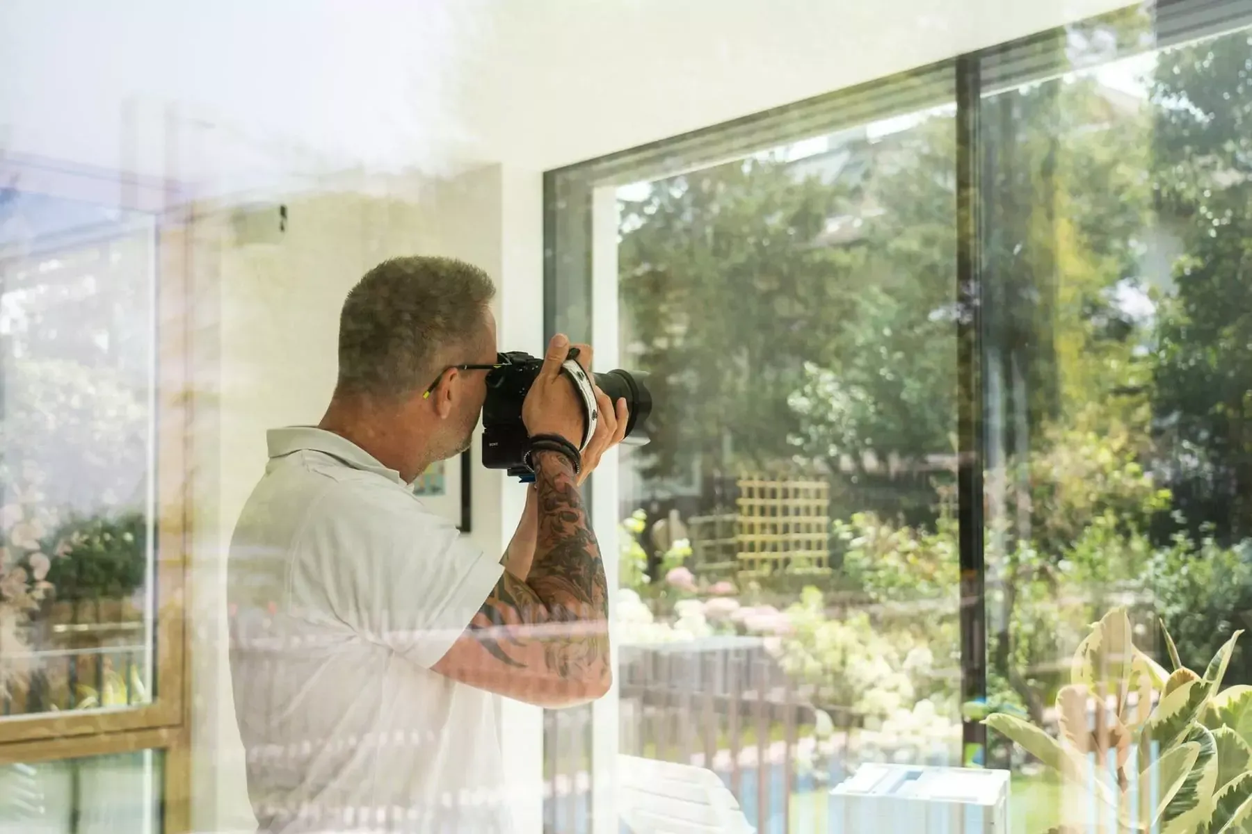 Ein Mann macht mit einer Kamera ein Foto von einem Fenster.