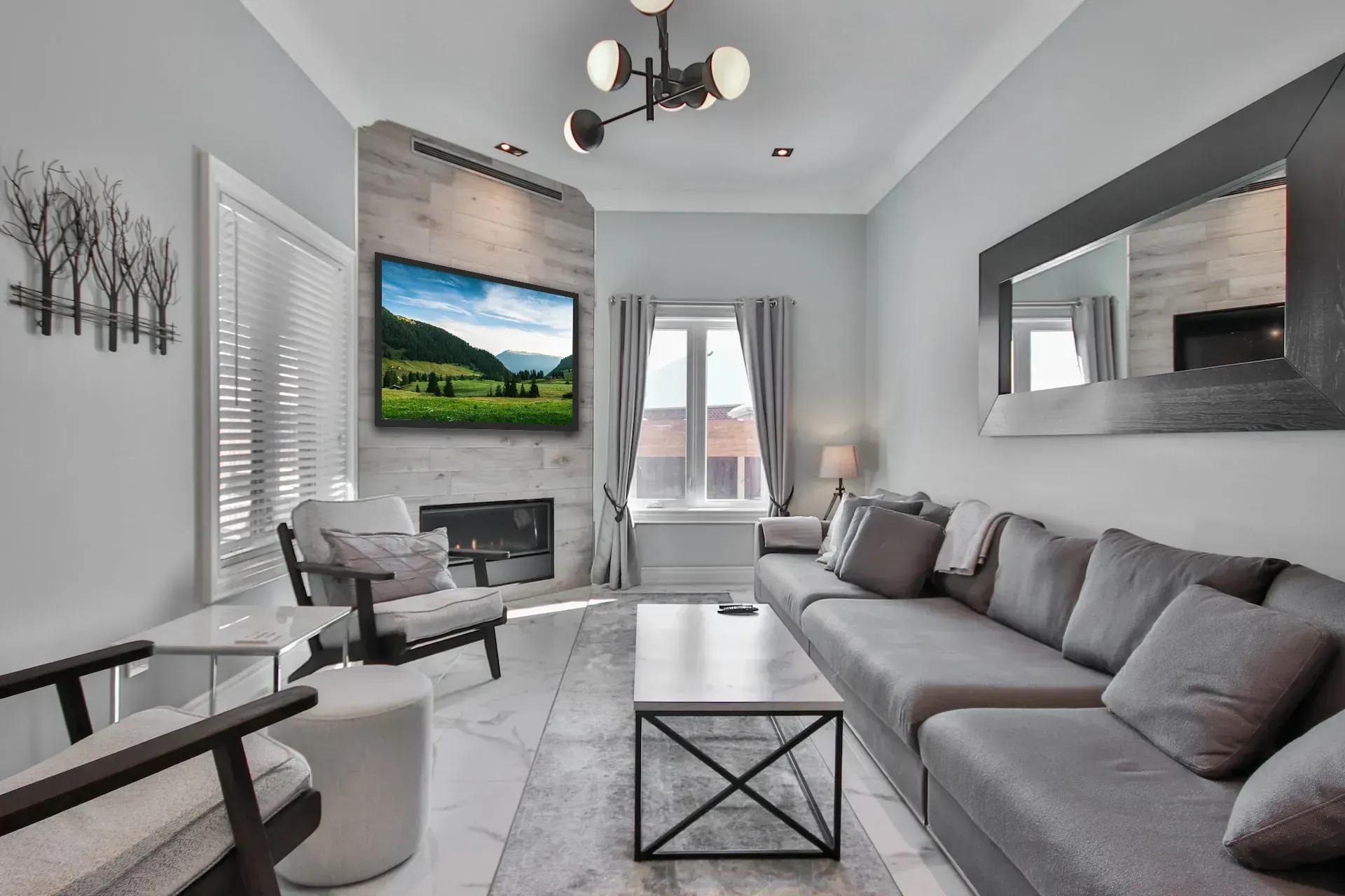 A living room with a couch , chairs , coffee table and television.