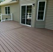 A wooden deck with a sliding glass door in front of a house.