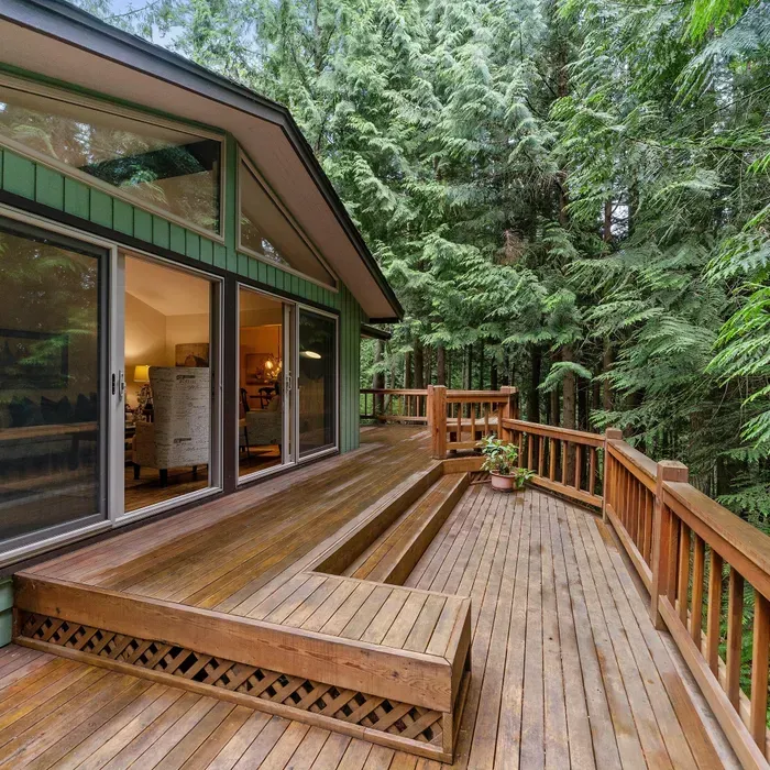 A house with a large wooden deck surrounded by trees