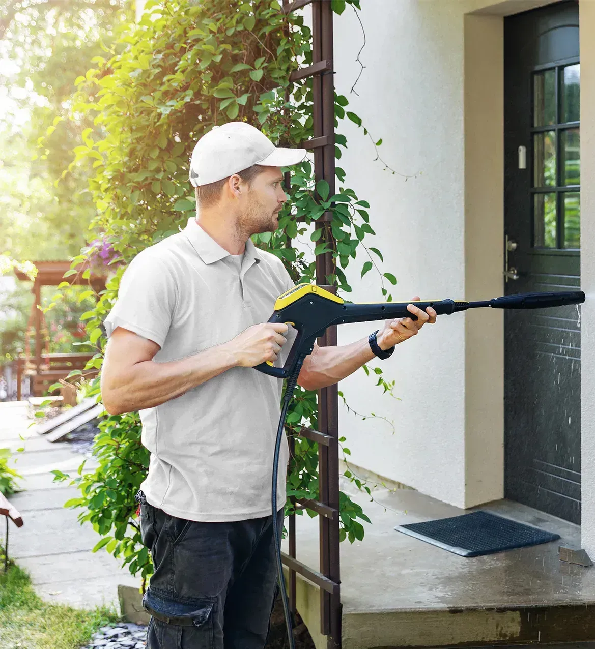 A man is holding a high pressure washer in front of a house.