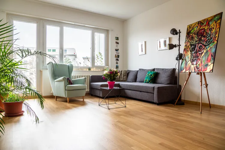 A living room with a couch , chair , table and painting on the wall.