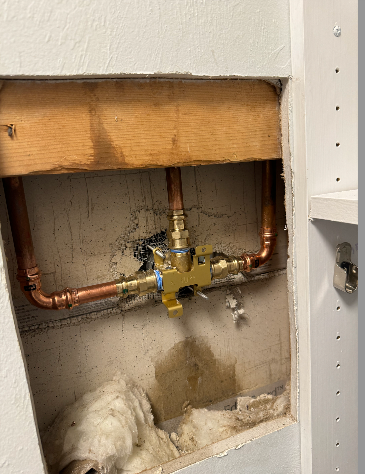 A bathroom sink with copper pipes coming out of the wall.