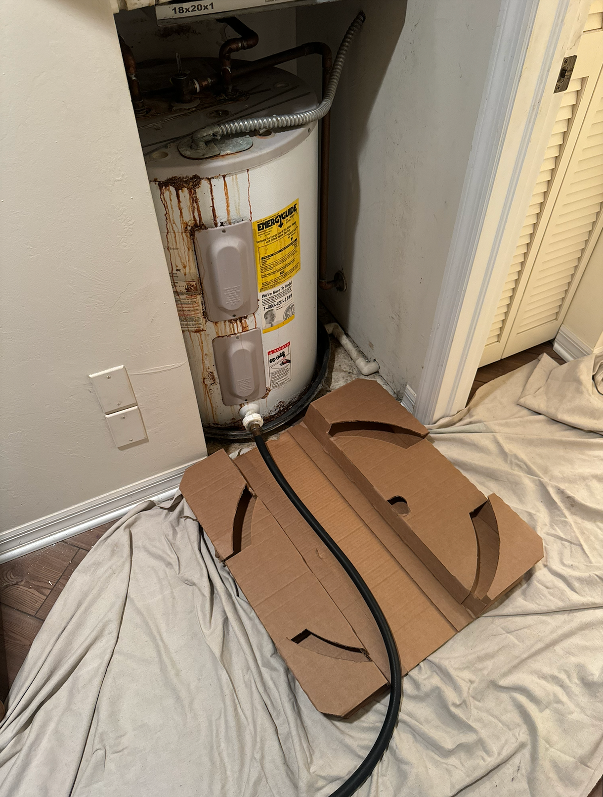 A water heater is sitting on top of a cardboard box.