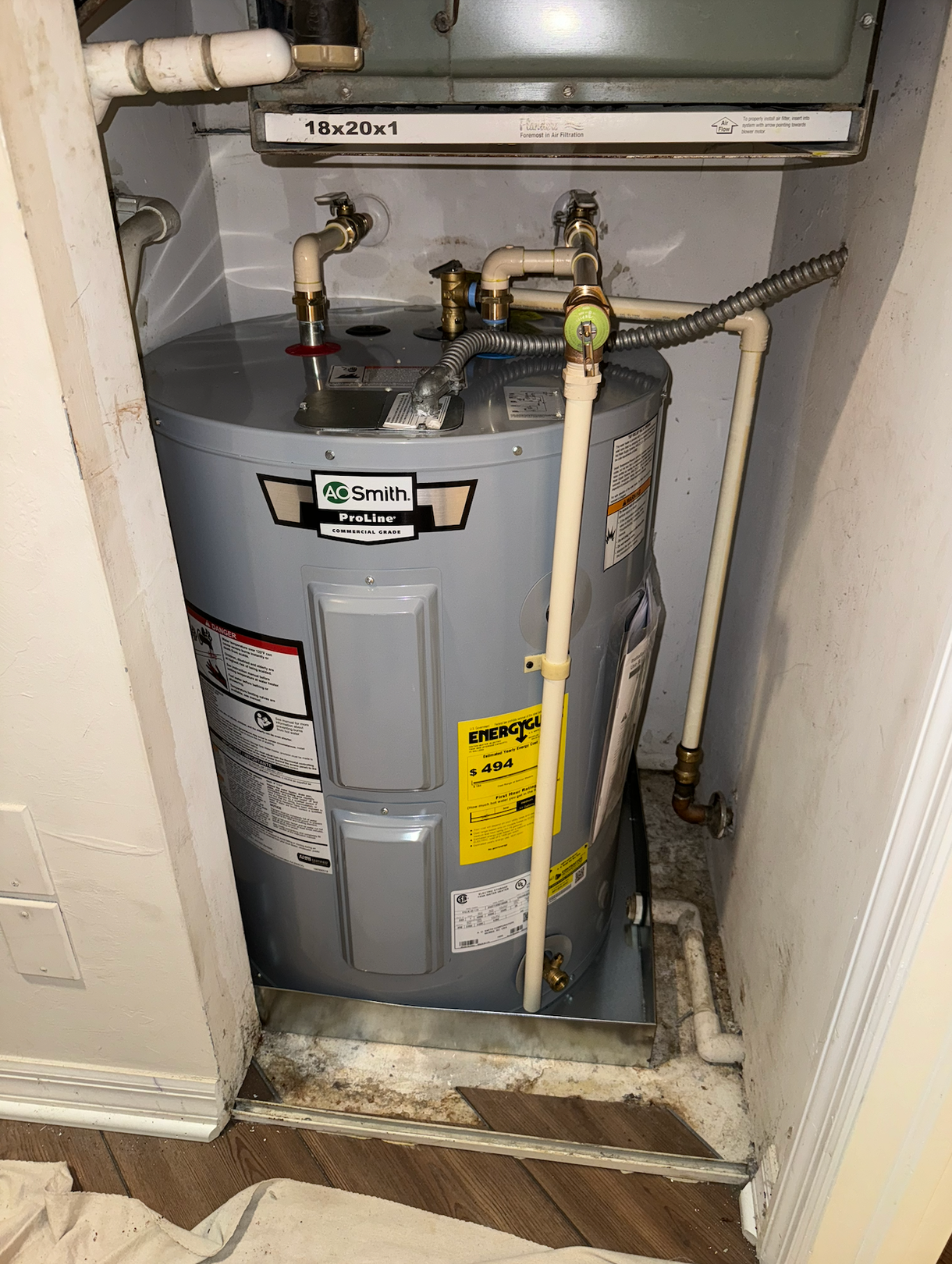 A water heater is sitting in a closet next to a furnace.