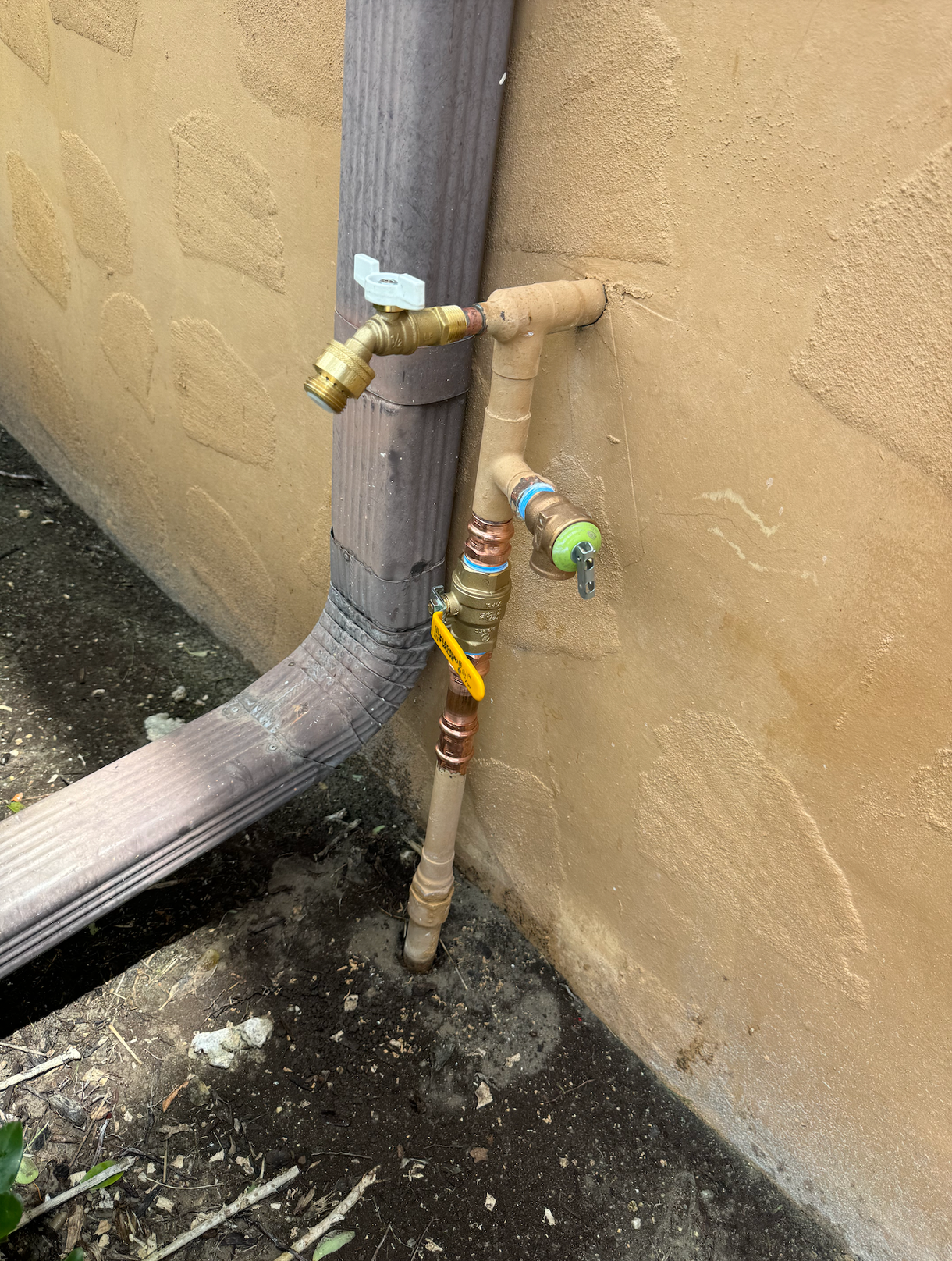 A faucet is attached to a pipe on the side of a building.