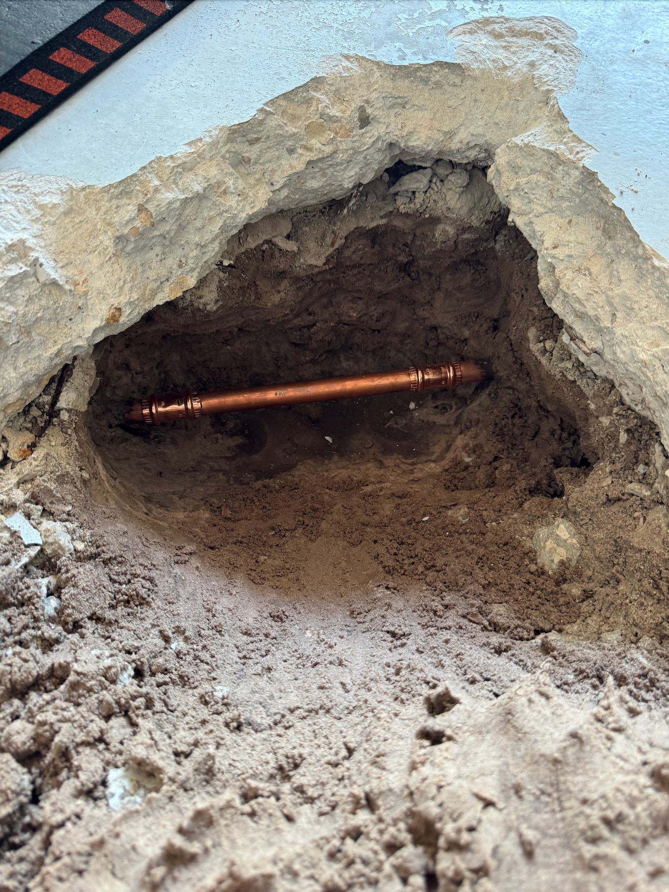 Tarpon Plumbing & Drains - A copper pipe is sticking out of a hole in the ground.