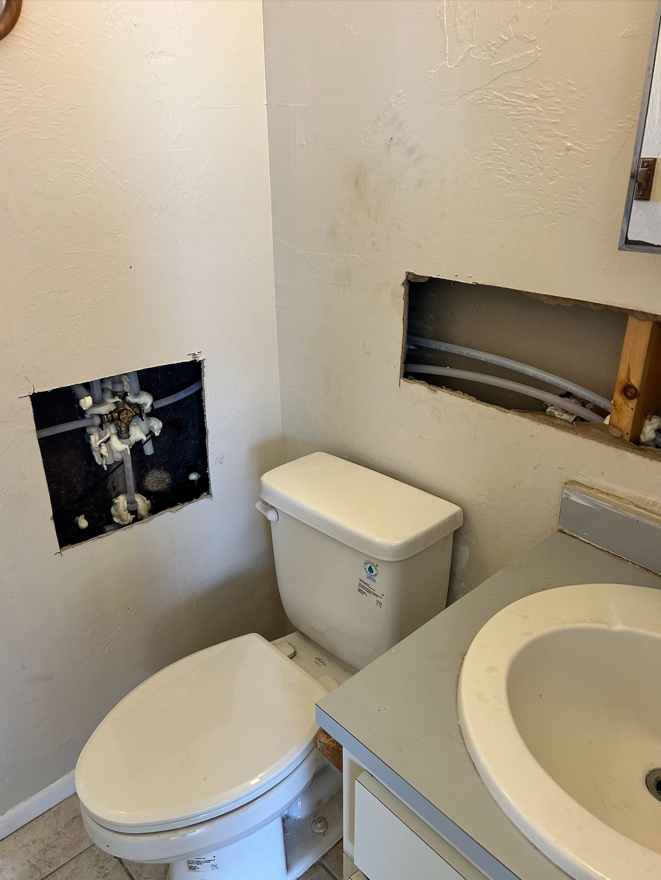 Tarpon Plumbing & Drains - A bathroom with a toilet , sink and a hole in the wall.