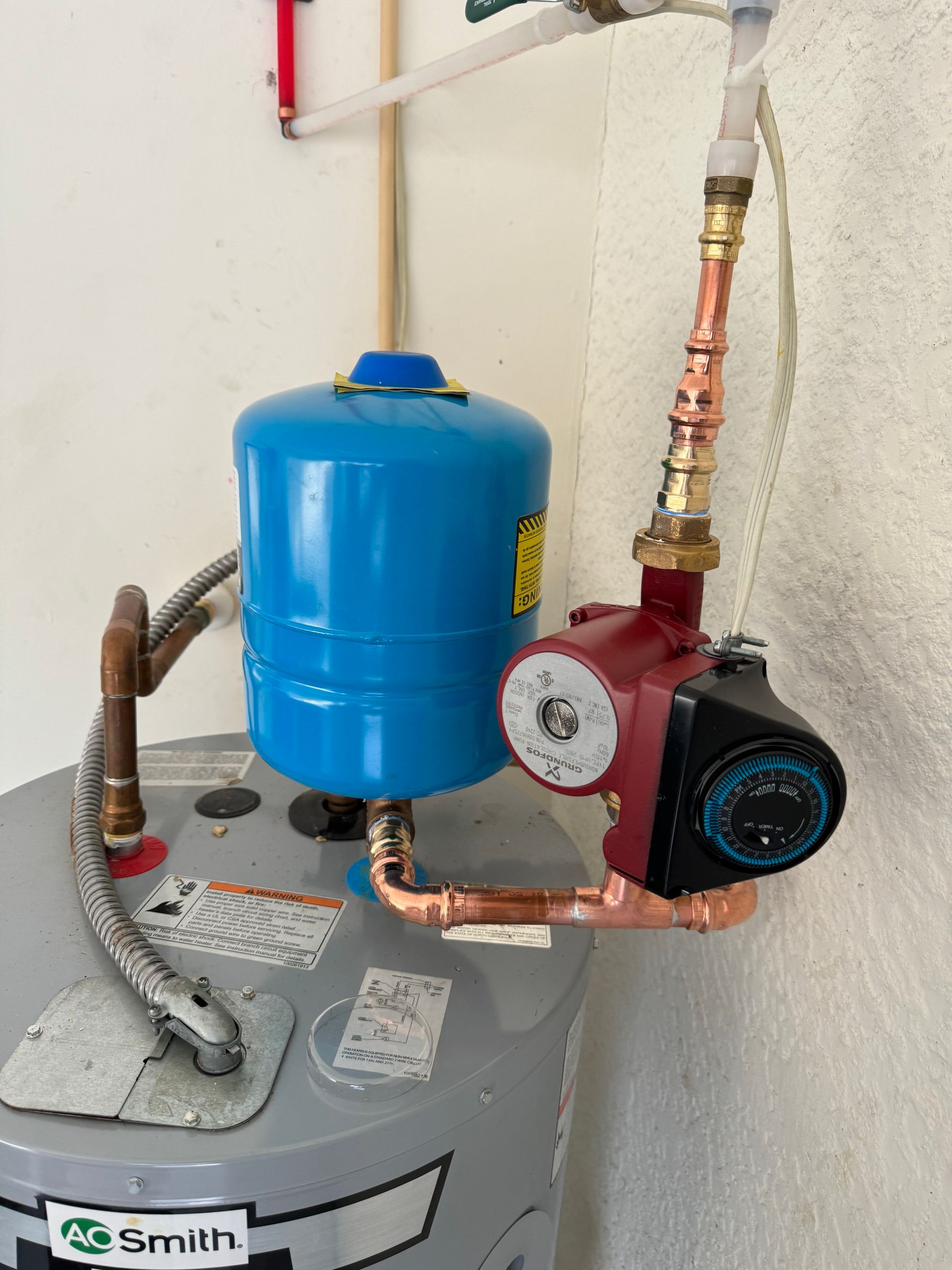 Tarpon Plumbing & Drains - A water heater with a blue tank and a pump attached to it.