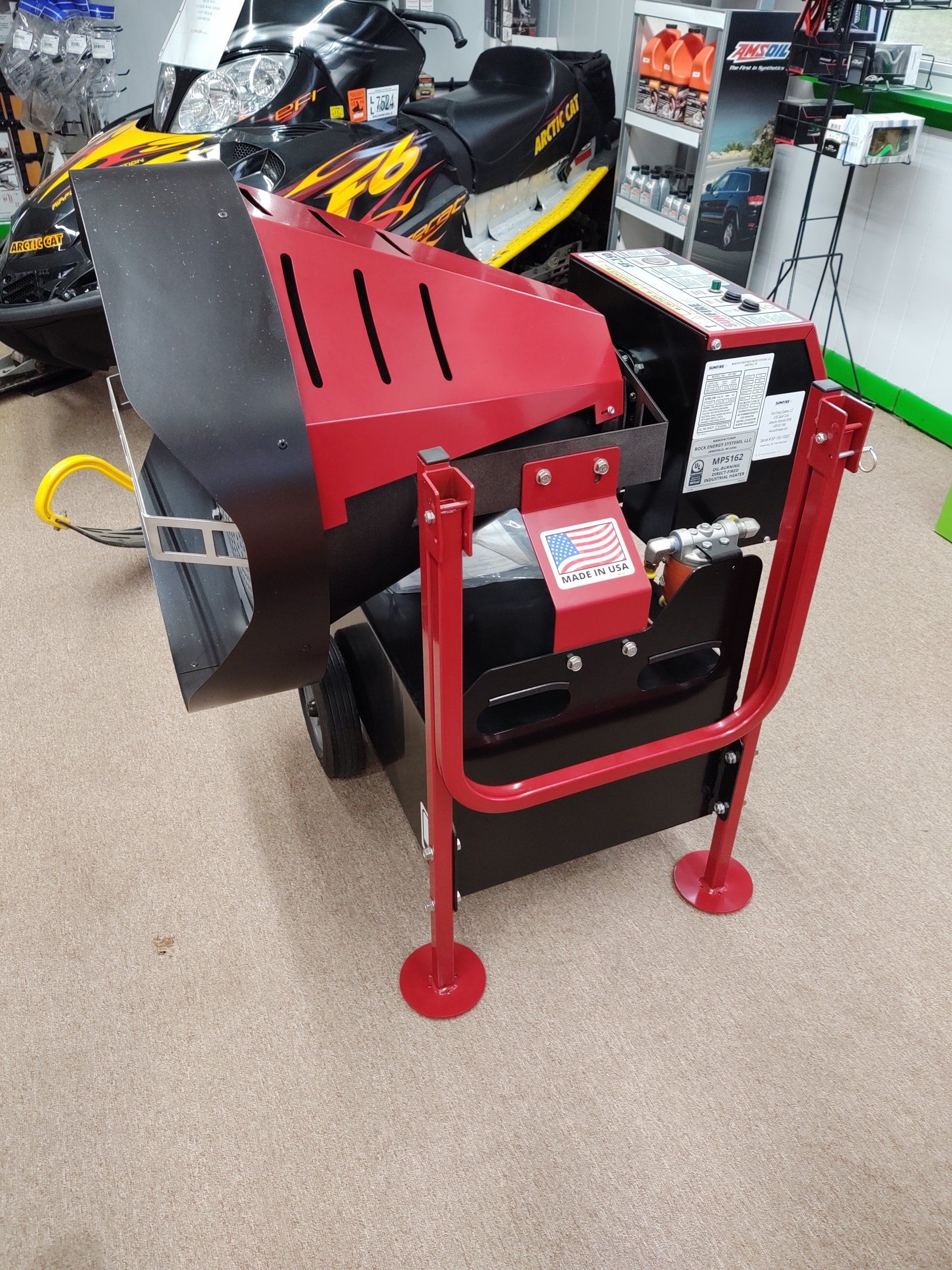 A red and black machine is sitting on a carpeted floor.