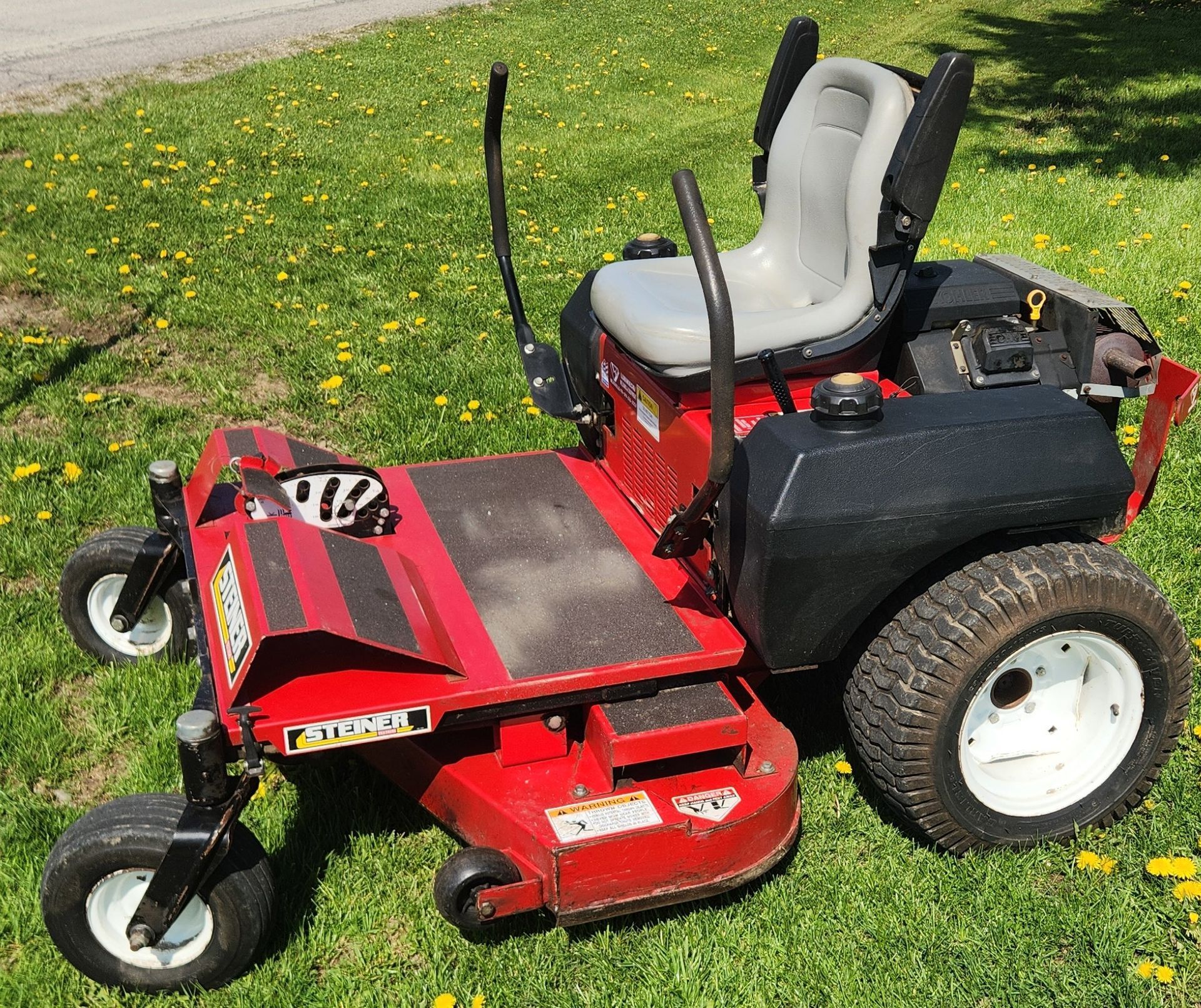 Red riding lawn mower parked on grass, with a black bagging attachment and gray seat.