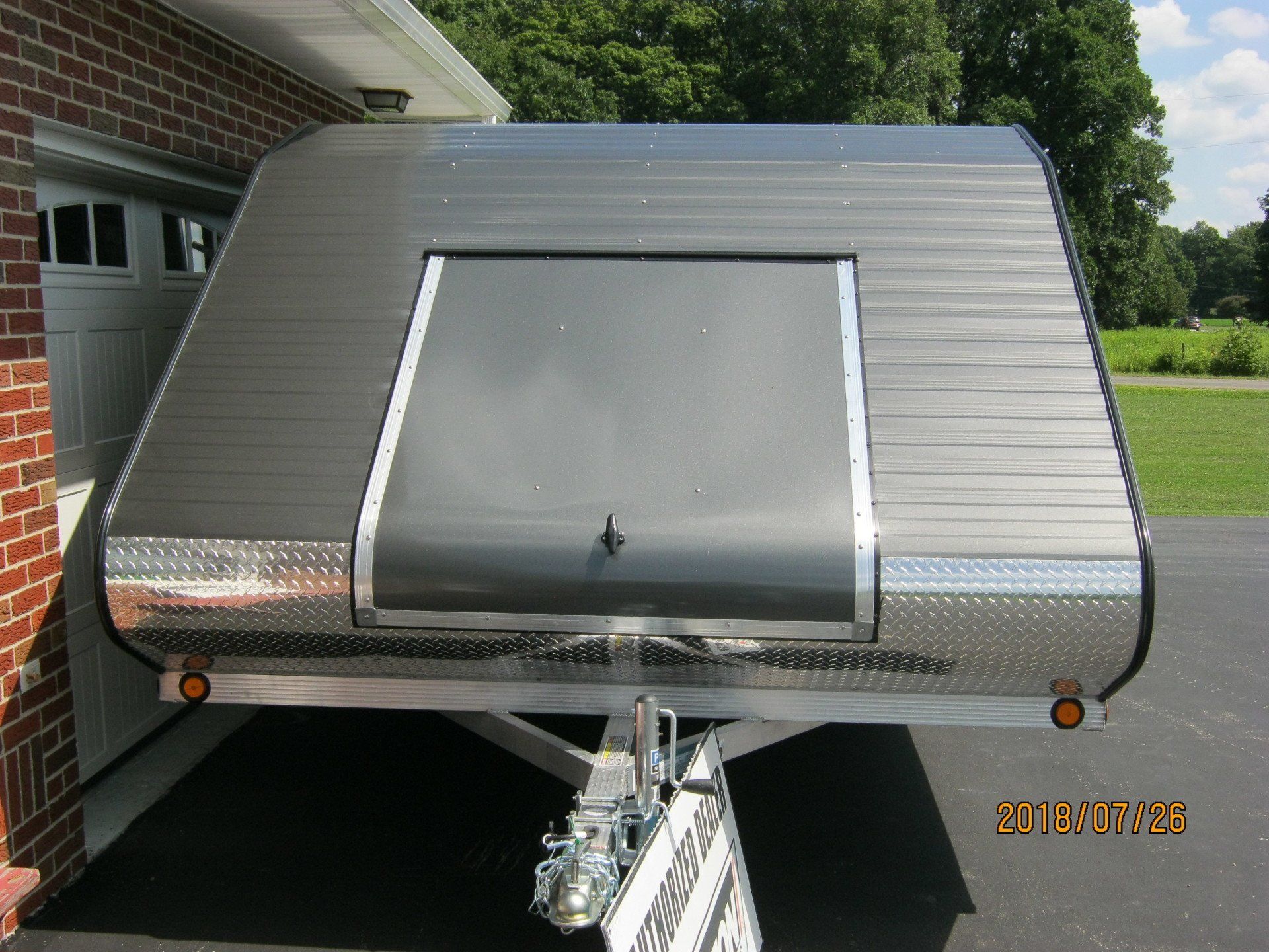 A silver trailer is parked in front of a brick building