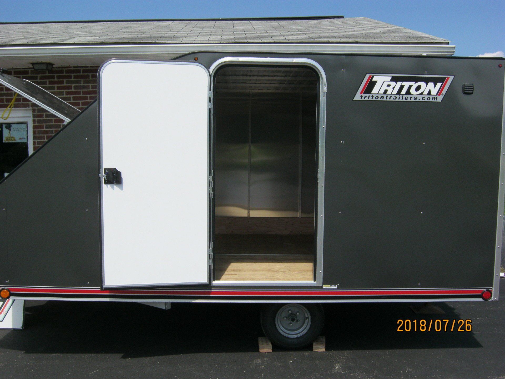 A triton trailer is parked in front of a brick building