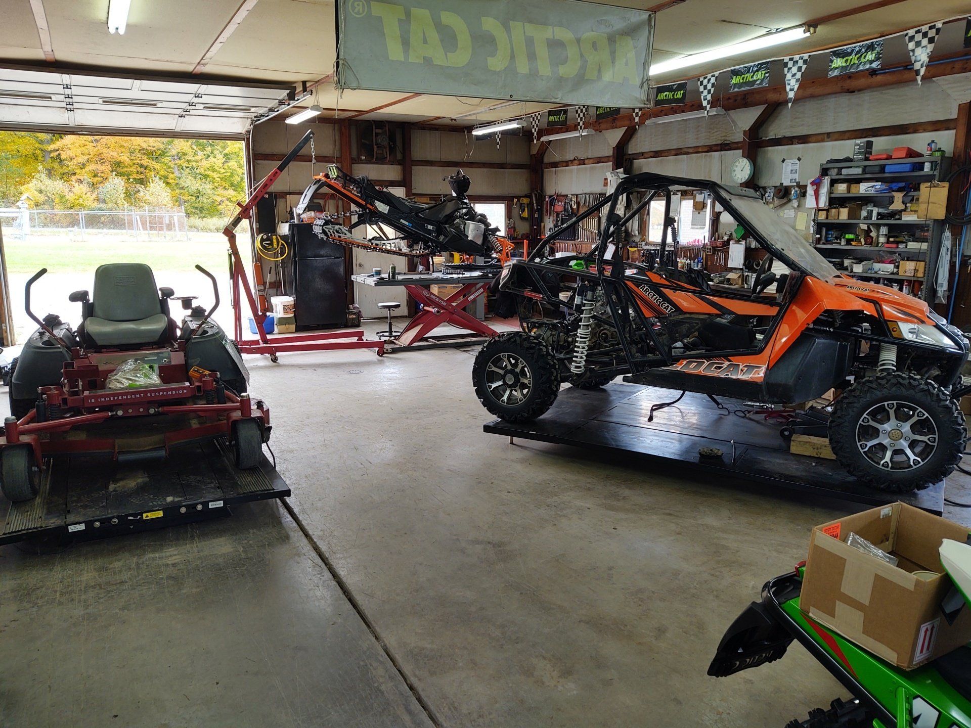 A garage with a lawn mower and a buggy in it
