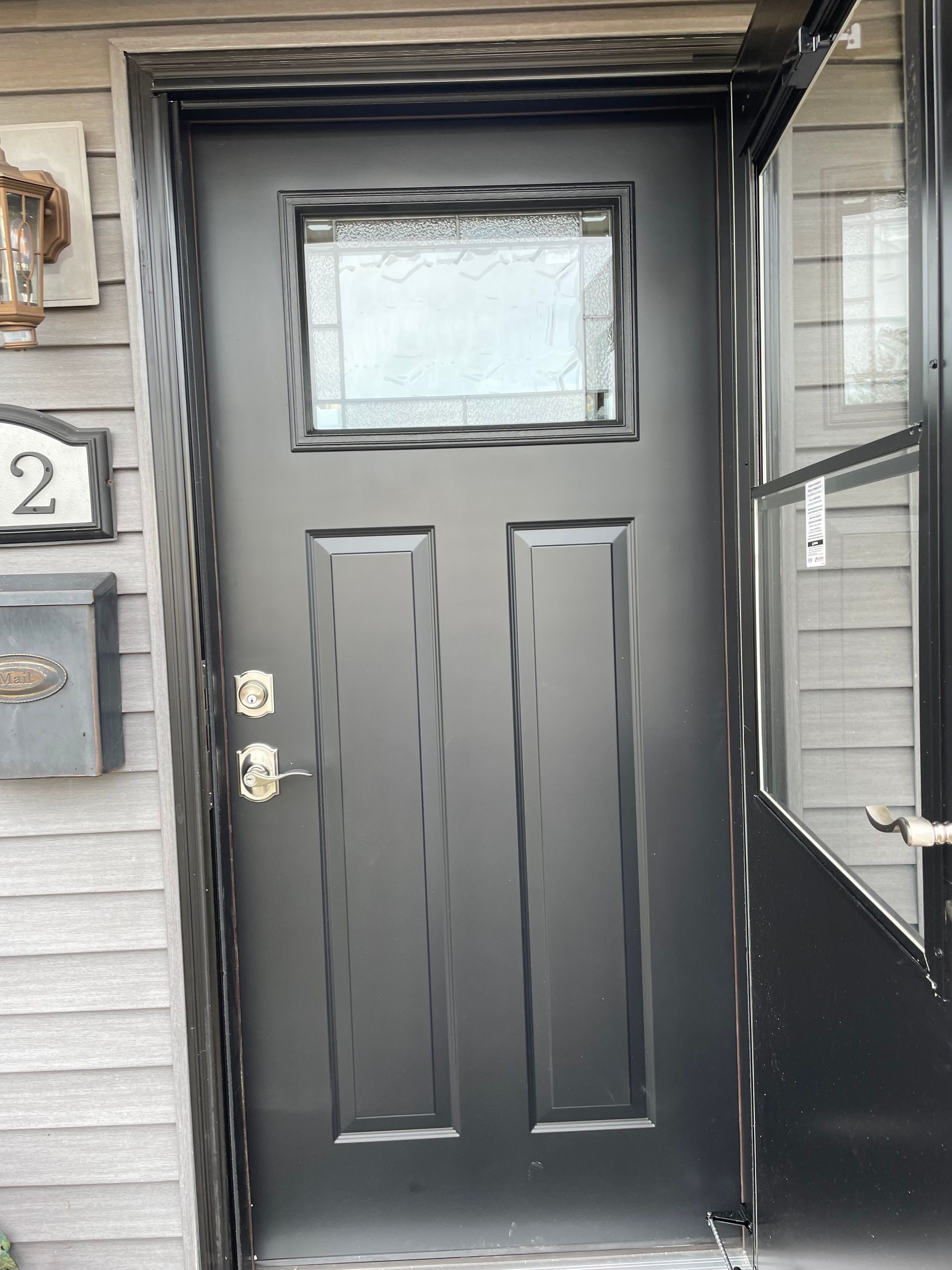 A black door with a small window is on the side of a house.