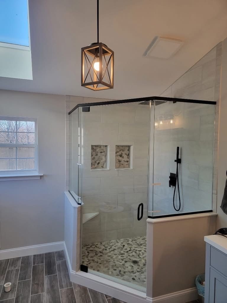 A bathroom with a walk in shower and a window.