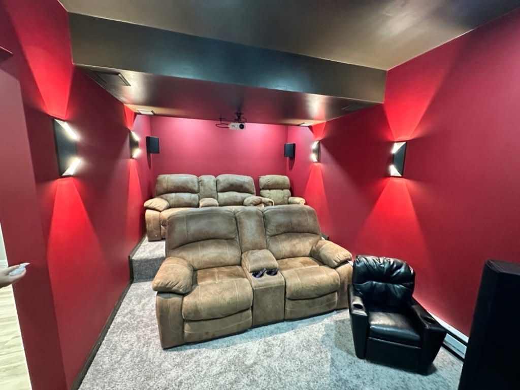 A home theater with a couch , chair , and projector.