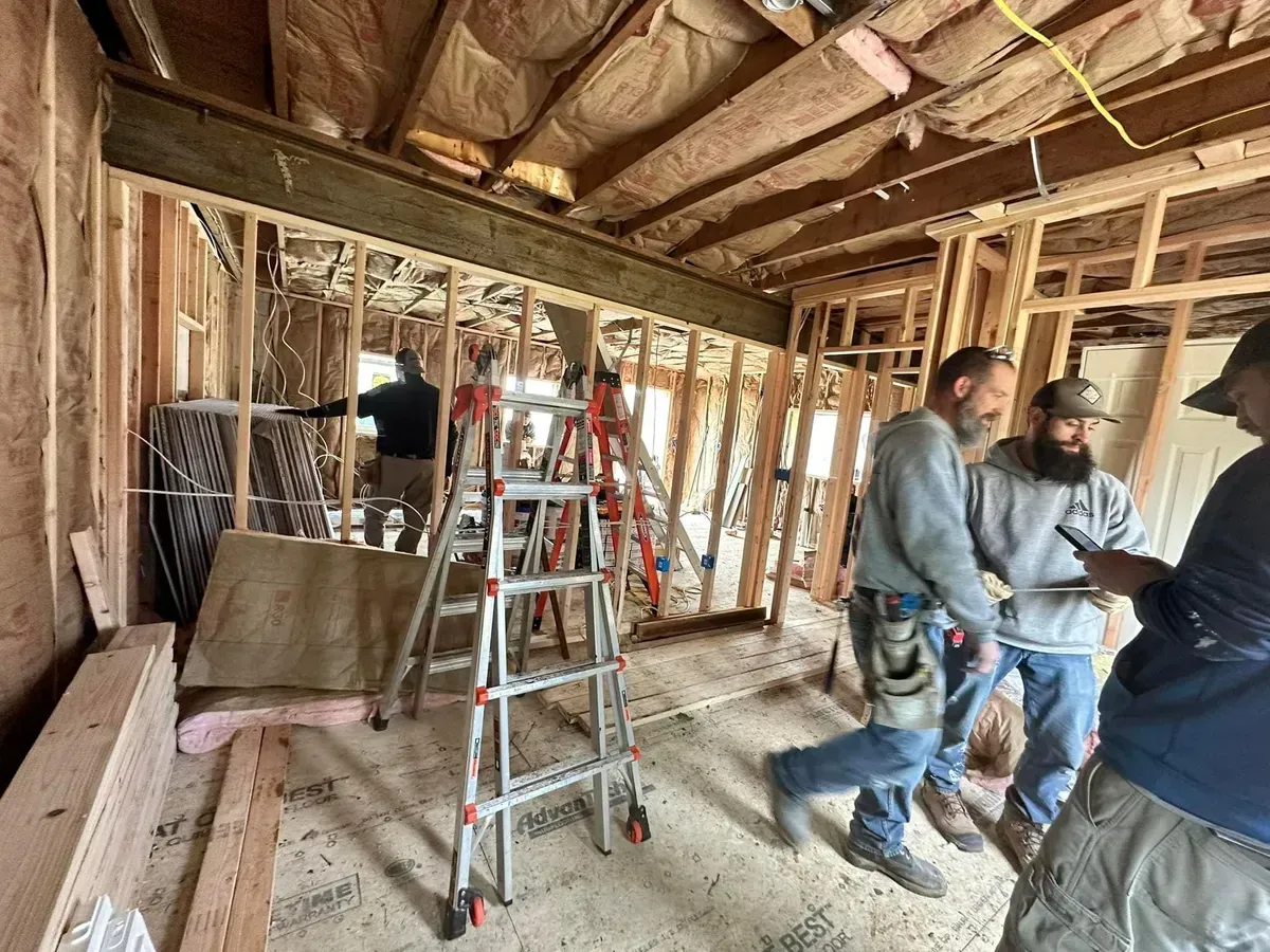 A group of men are standing in a room under construction.