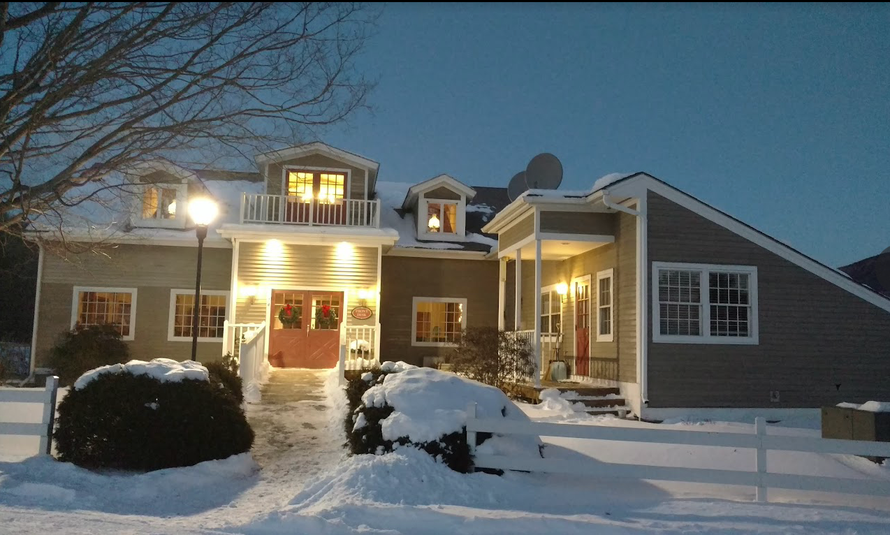 a house with a lot of windows is covered in snow