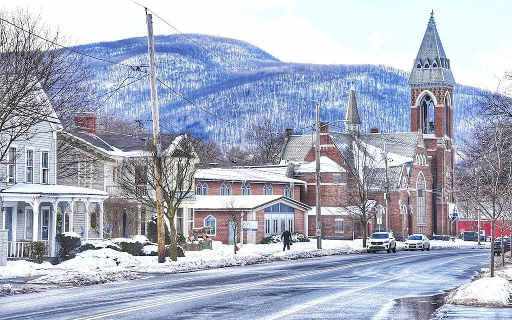 a snowy street with a church in the background and mountains in the background .